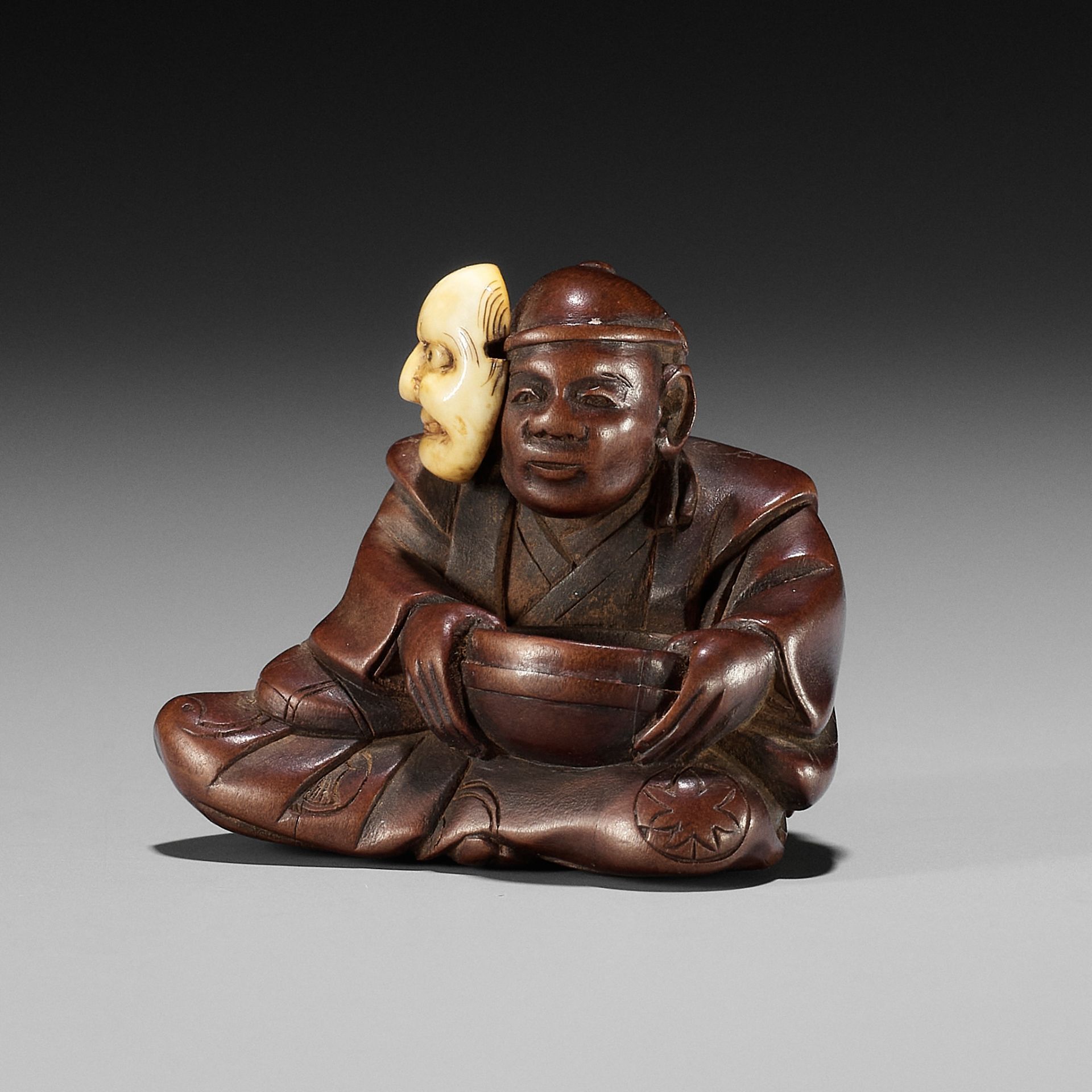 RYUSEI: A FINE WOOD NETSUKE OF AN ACTOR WITH A BUAKU MASK