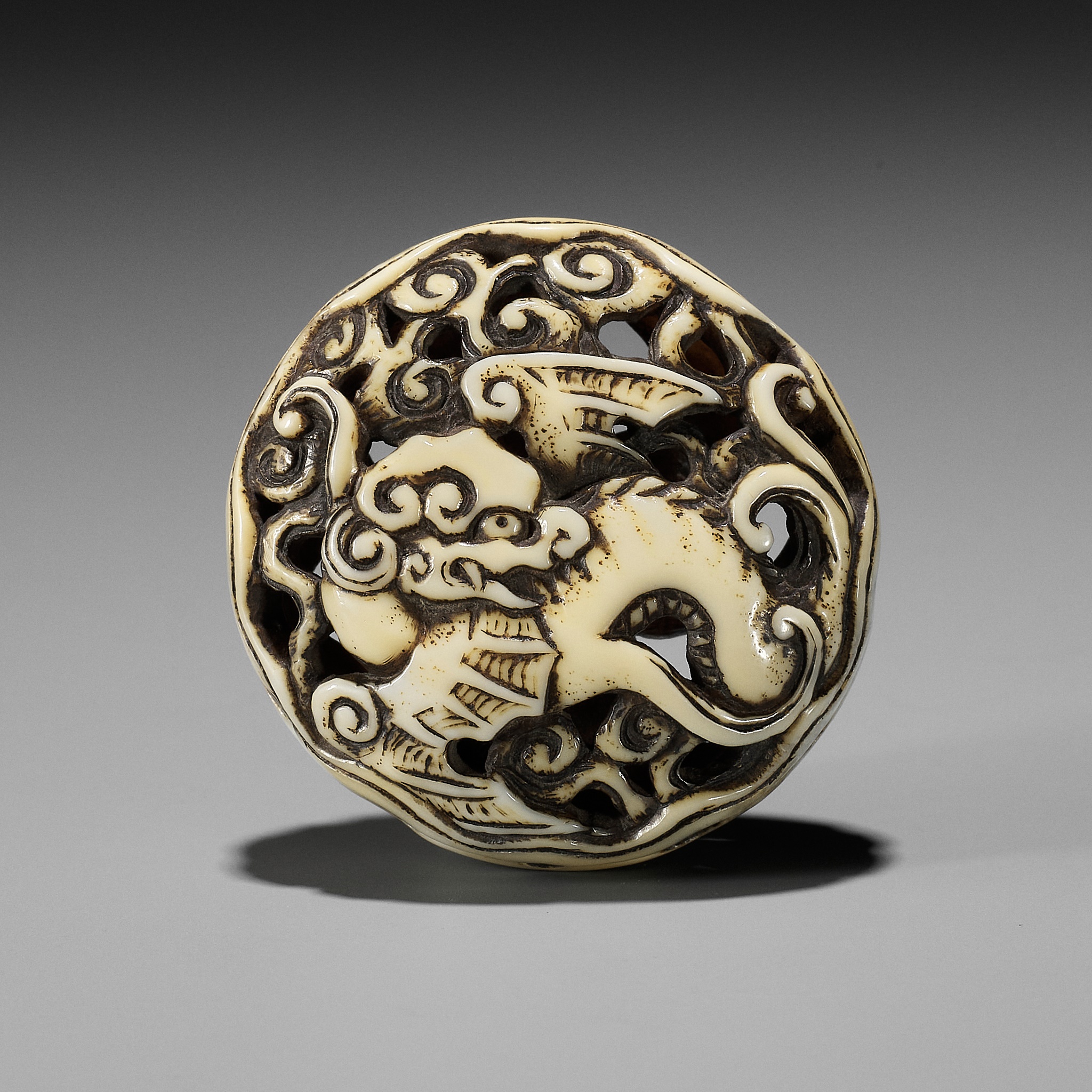 A WALRUS IVORY RYUSA MANJU NETSUKE OF A WINGED DRAGON