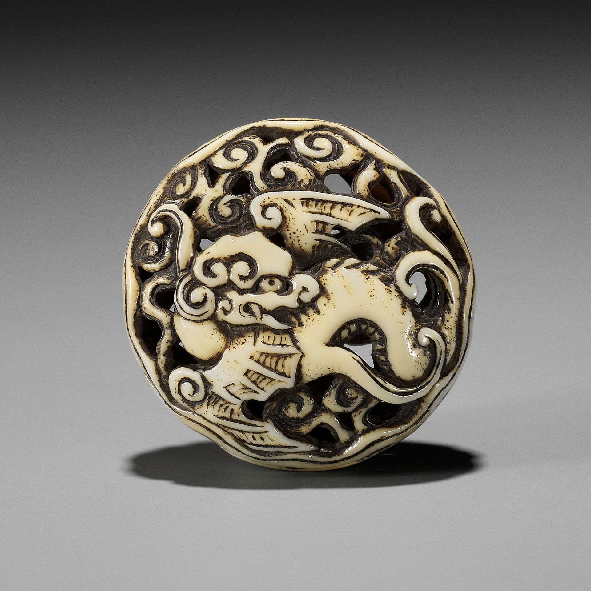 A WALRUS IVORY RYUSA MANJU NETSUKE OF A WINGED DRAGON