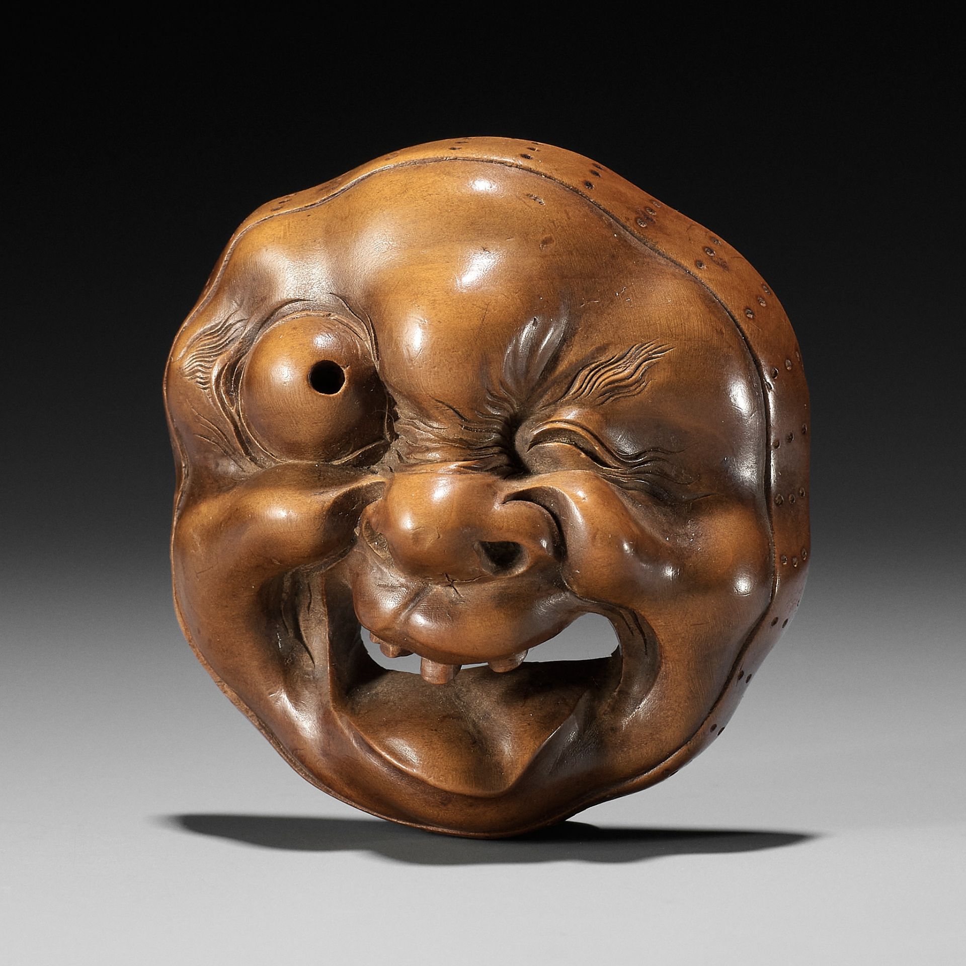 A LARGE AND SUPERB WOOD MASK NETSUKE OF A GROTESQUELY GRIMACING MAN, ATTRIBUTED TO KOKEISAI SANSHO