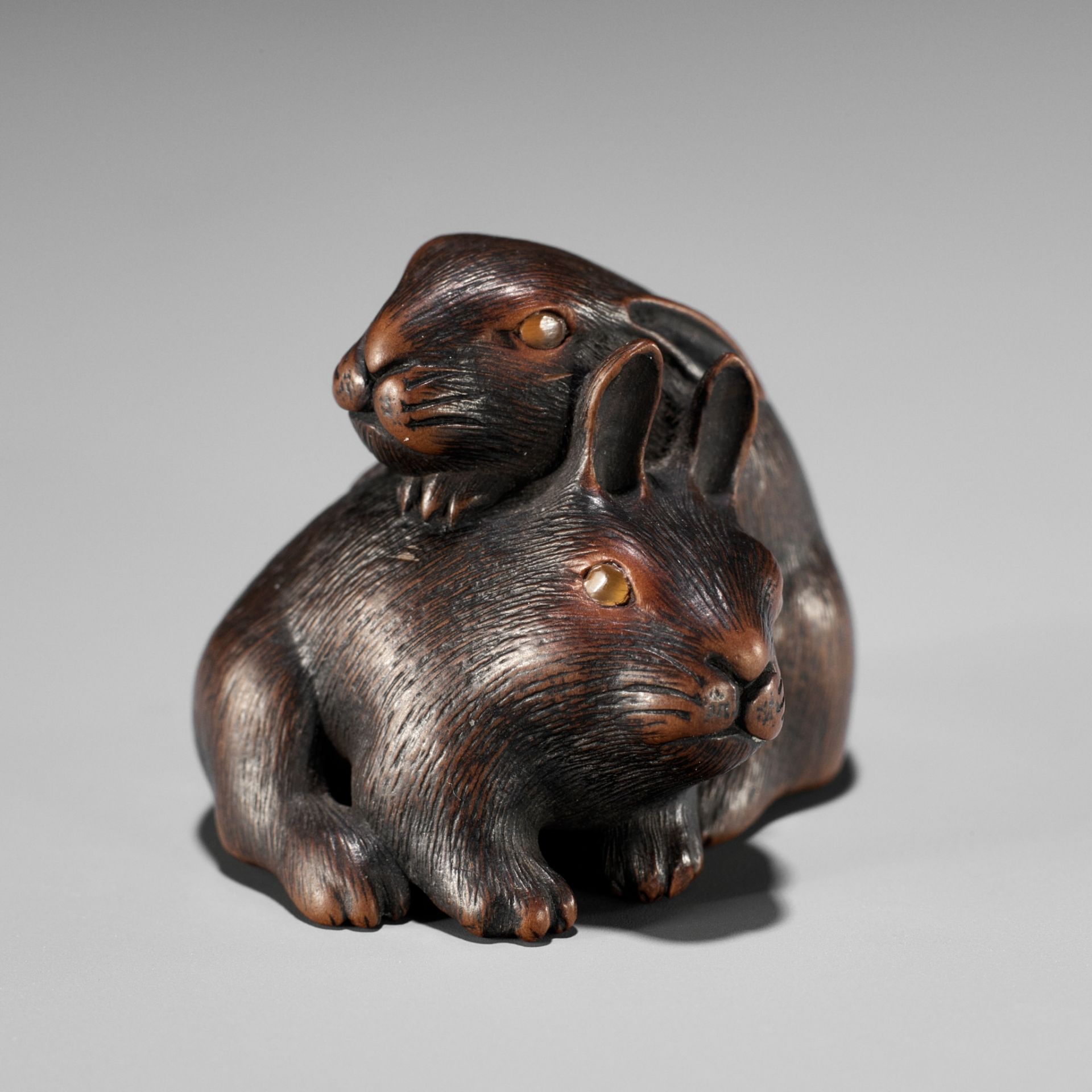 MASATADA: A FINE WOOD NETSUKE OF TWO RABBITS WITH AMBER EYES