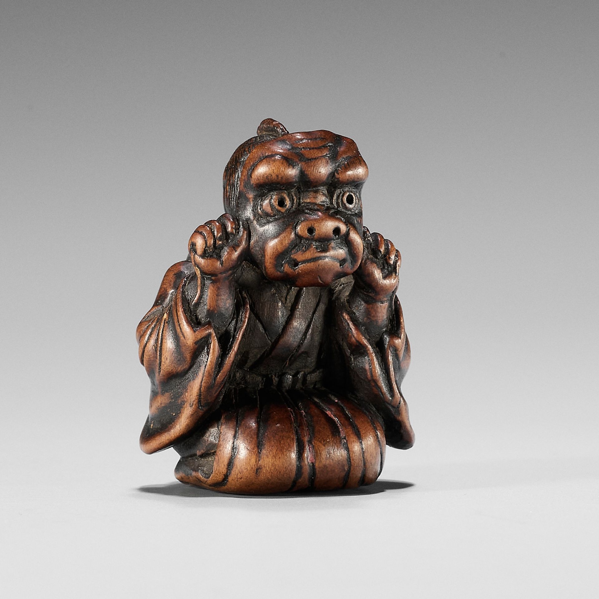 A FINE EDO SCHOOL WOOD NETSUKE OF A BOY WEARING AN ONI MASK