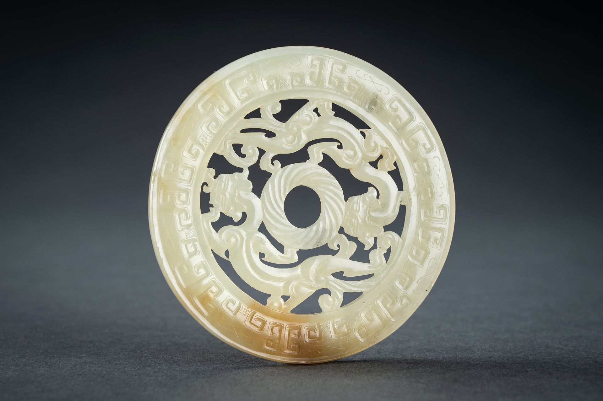 AN ARCHAISTIC YELLOW JADE RETICULATED 'CHILONG' BI DISC, QING