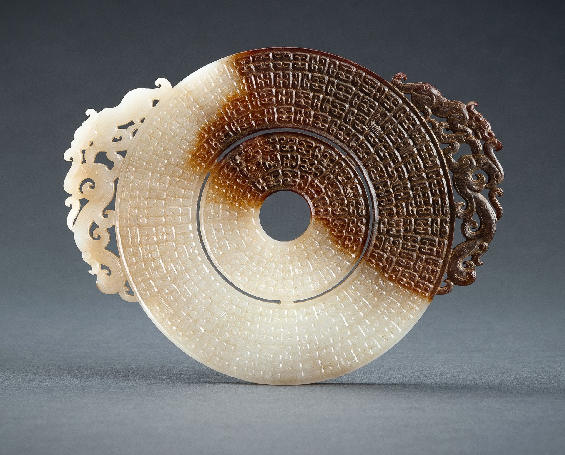 AN ARCHAISTIC WHITE AND BROWN JADE DOUBLE BI DISC, QING