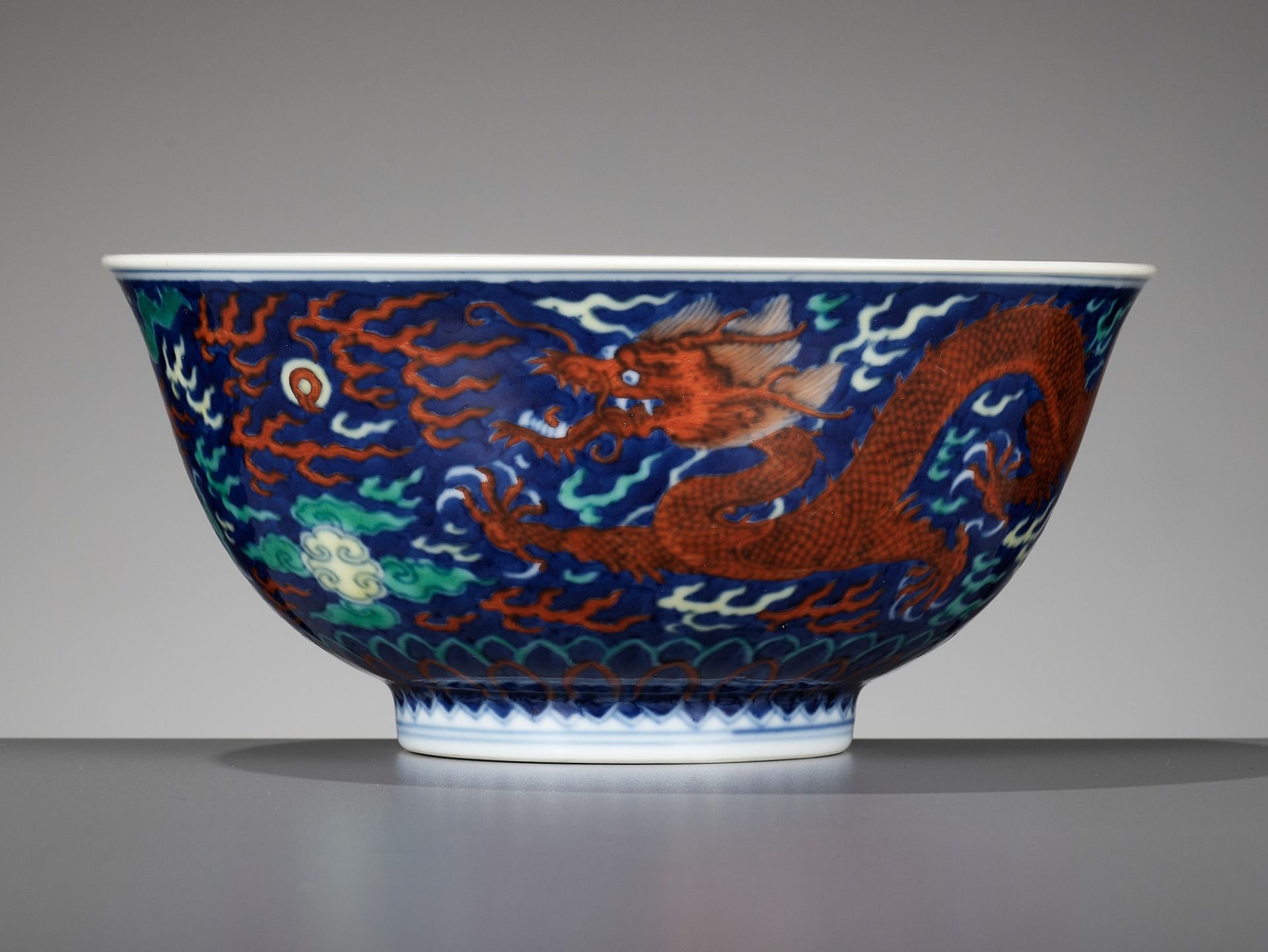 A RARE BLUE-GROUND POLYCHROME-DECORATED 'DRAGON' BOWL, QIANLONG MARK AND PERIOD