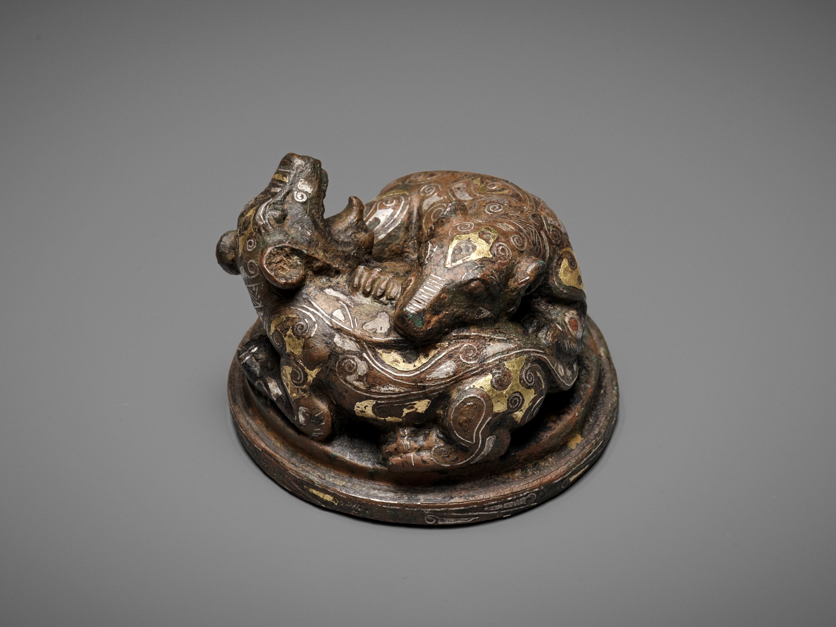 A GOLD AND SILVER-INLAID 'FIGHTING BEARS' BRONZE MAT WEIGHT, WARRING STATES TO HAN DYNASTY