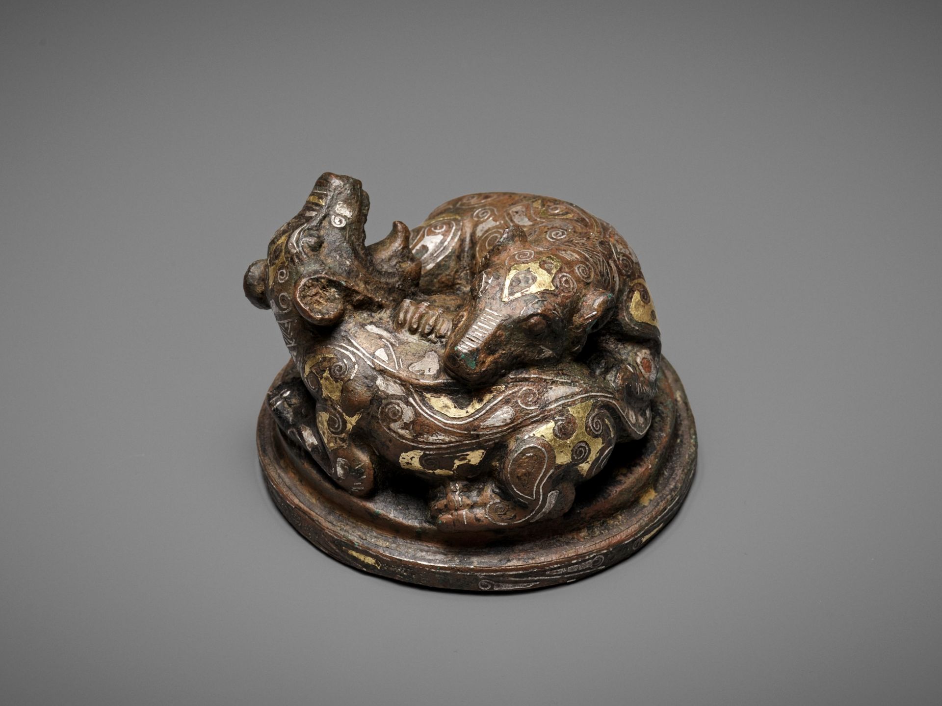 A GOLD AND SILVER-INLAID 'FIGHTING BEARS' BRONZE MAT WEIGHT, WARRING STATES TO HAN DYNASTY