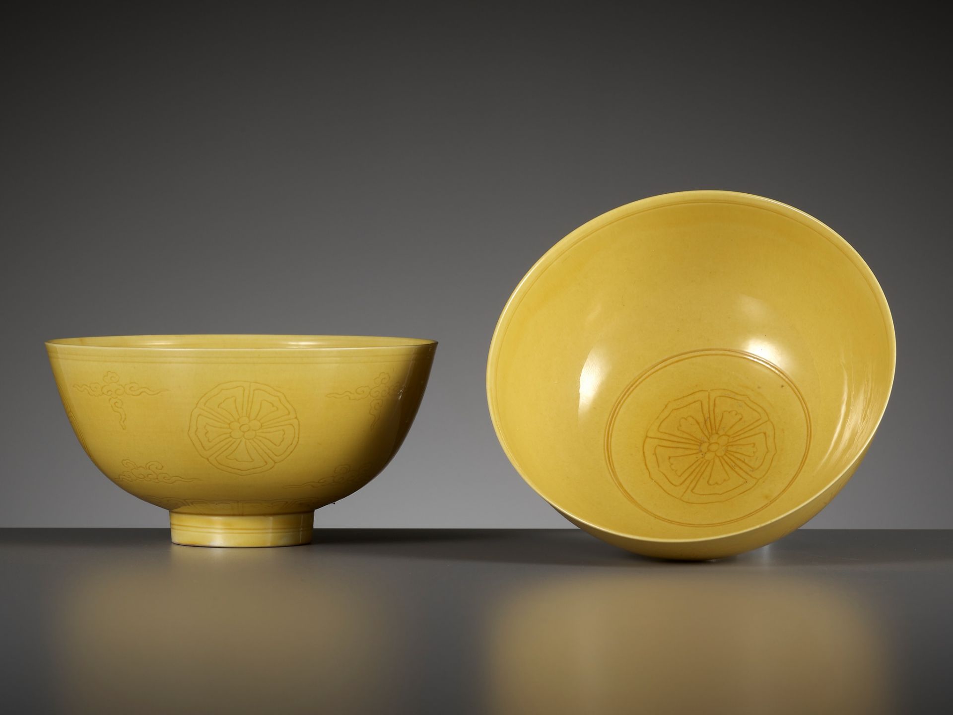 AN EXCEEDINGLY RARE PAIR OF INCISED YELLOW-GLAZED 'FLORAL MEDALLION' BOWLS, KANGXI MARKS AND PERIOD