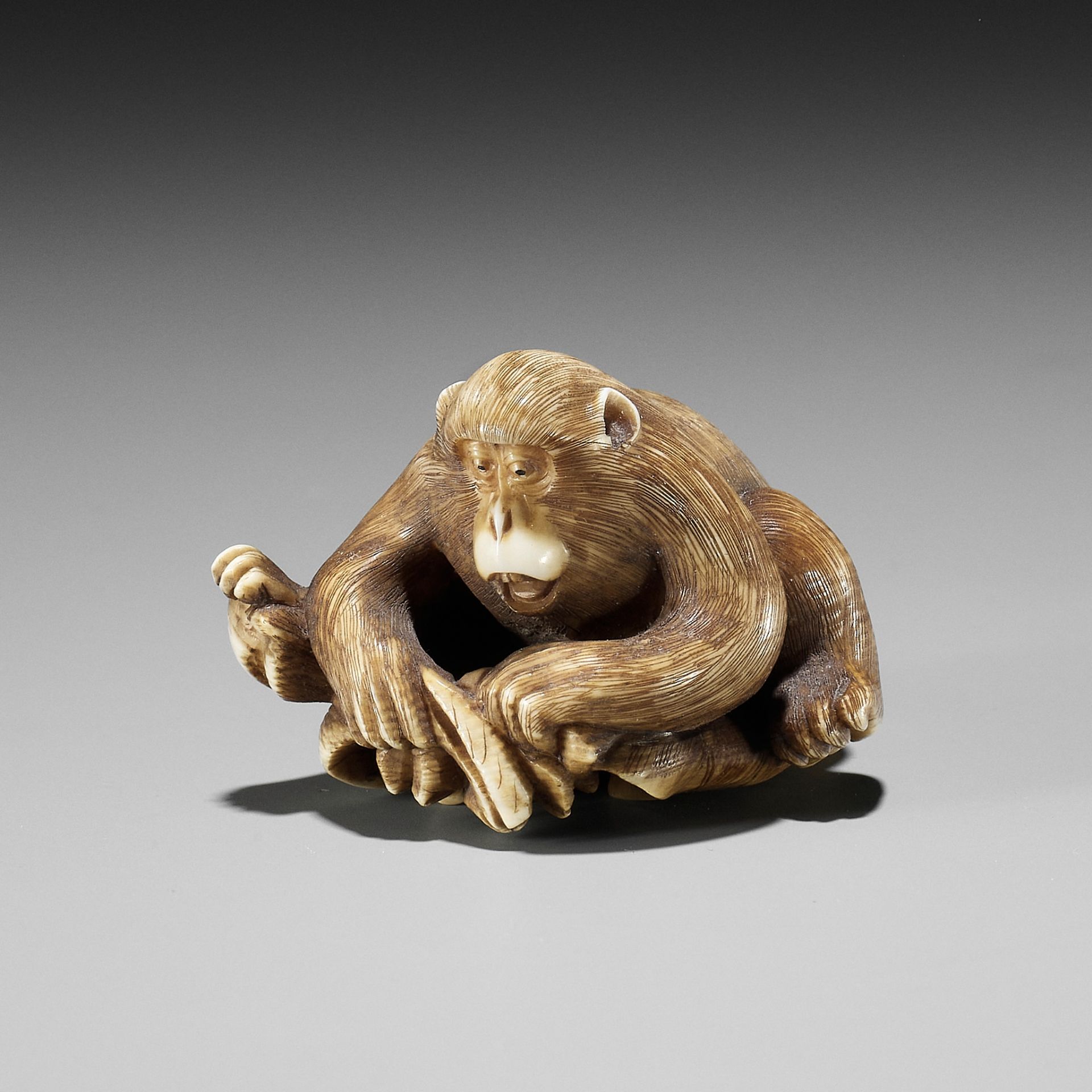 AN IVORY NETSUKE OF A MONKEY, CRAB AND LOTUS