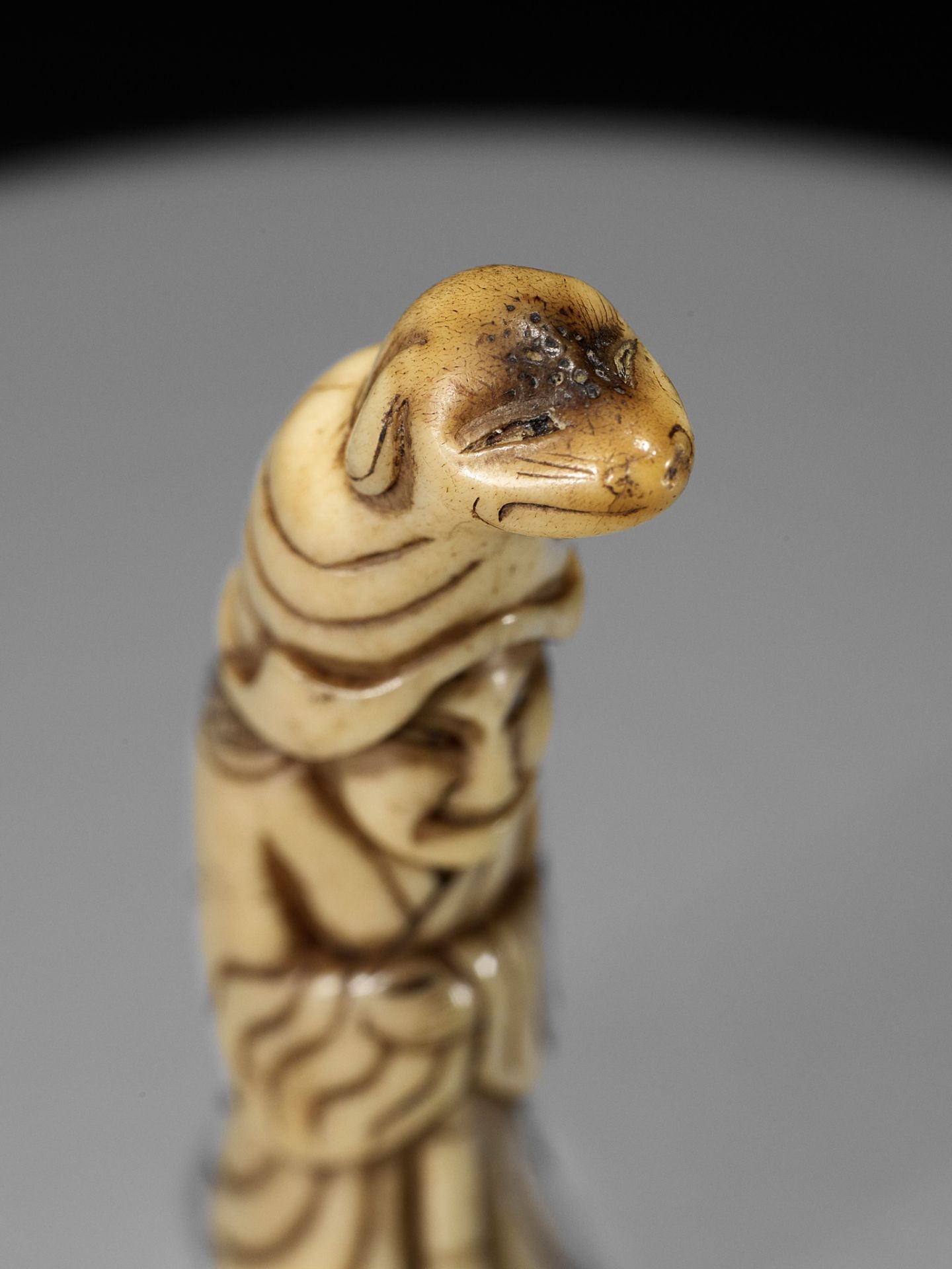 A RARE STAG ANTLER NETSUKE OF A PUPPETEER WITH A DOG PUPPET ON HIS HEAD