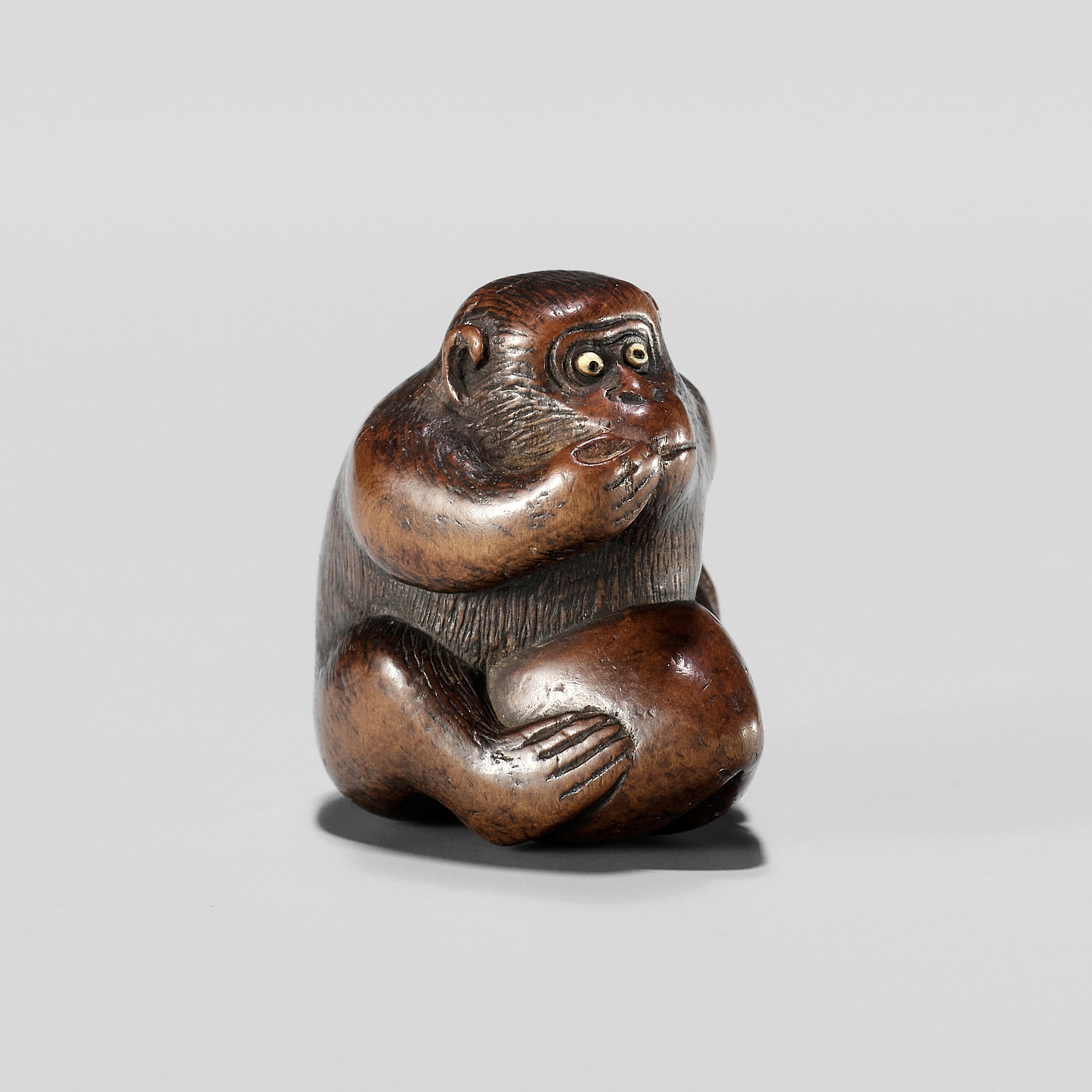 A WOOD NETSUKE OF A MONKEY EATING A PEACH, ATTRIBUTED TO MIWA