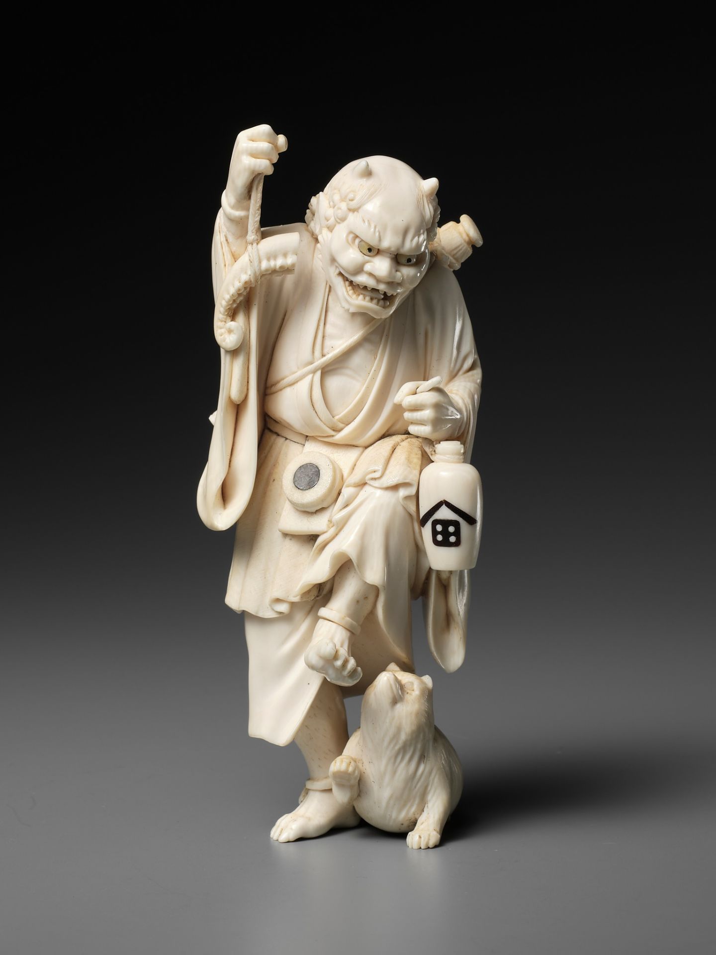MINJO: AN IVORY OKIMONO OF A DRUNKEN ONI WITH TANUKI