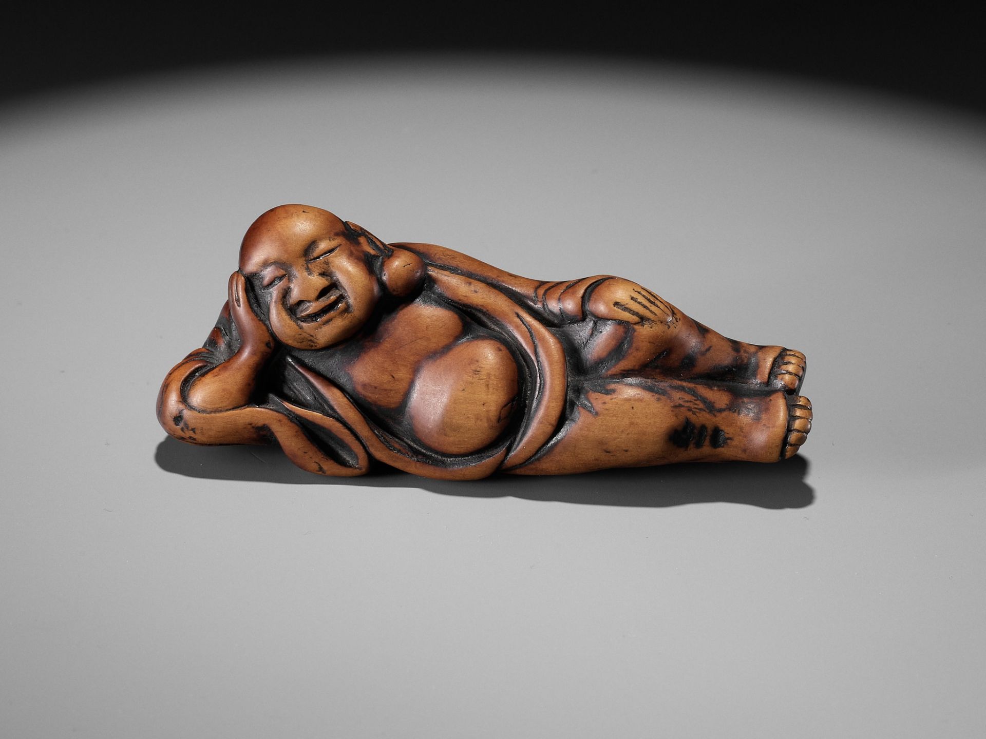 AN EARLY WOOD NETSUKE OF A RECLINING HOTEI