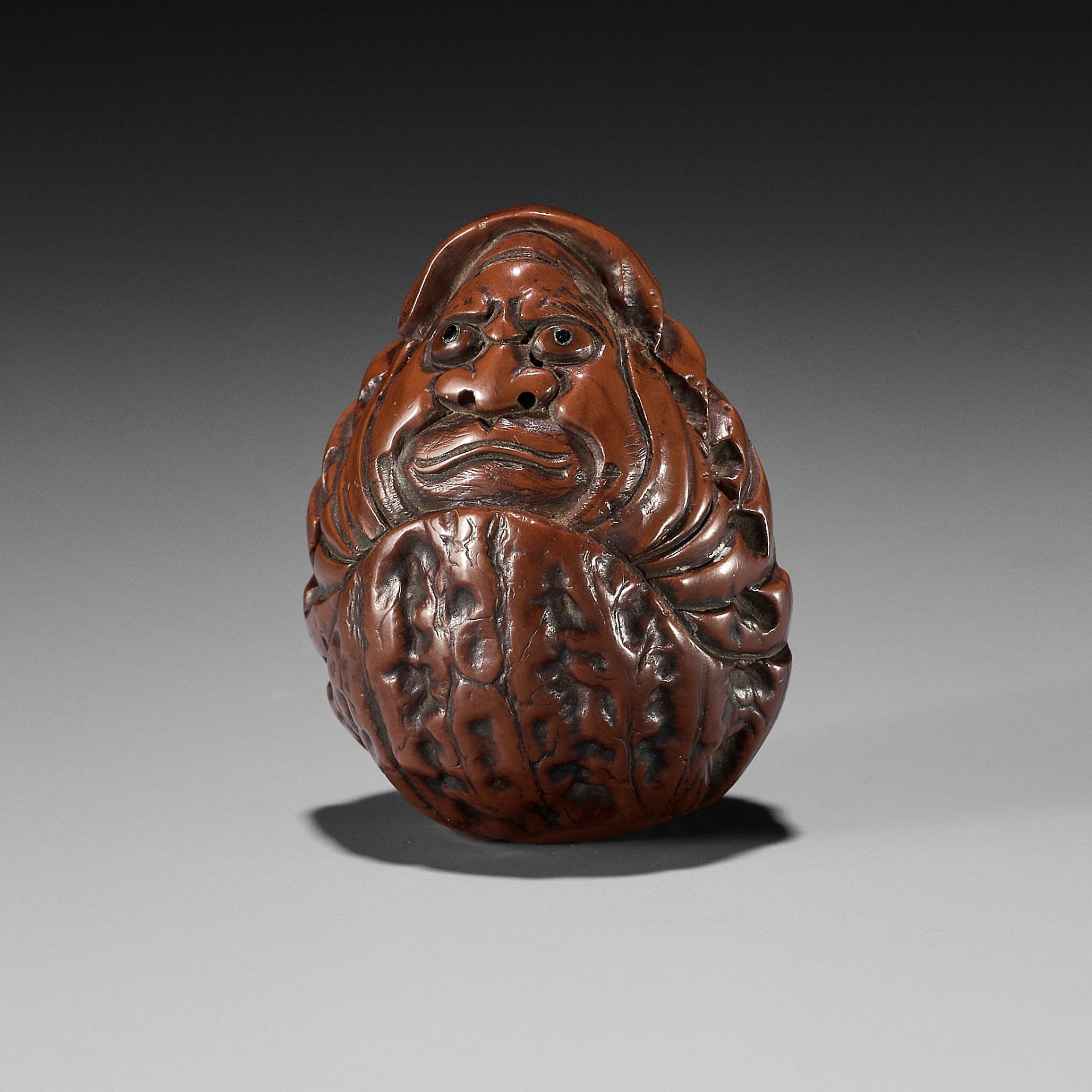 HIDARI ISSAN: A KURUMI (WALNUT) NETSUKE OF A ROLY POLY DARUMA