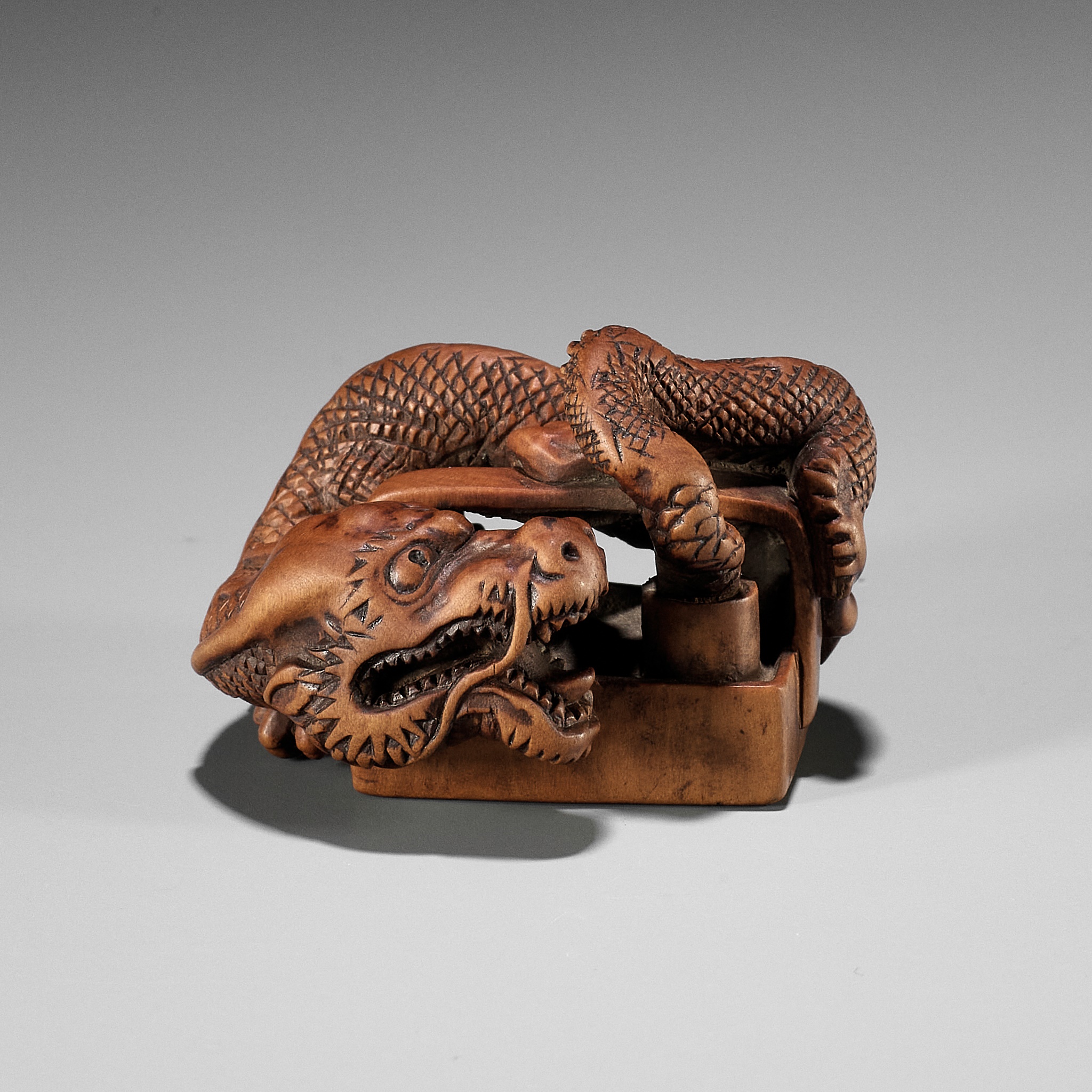 A WOOD NETSUKE OF A DRAGON EMERGING FROM AN ASH POT (HAIFUKI KARA RYU)