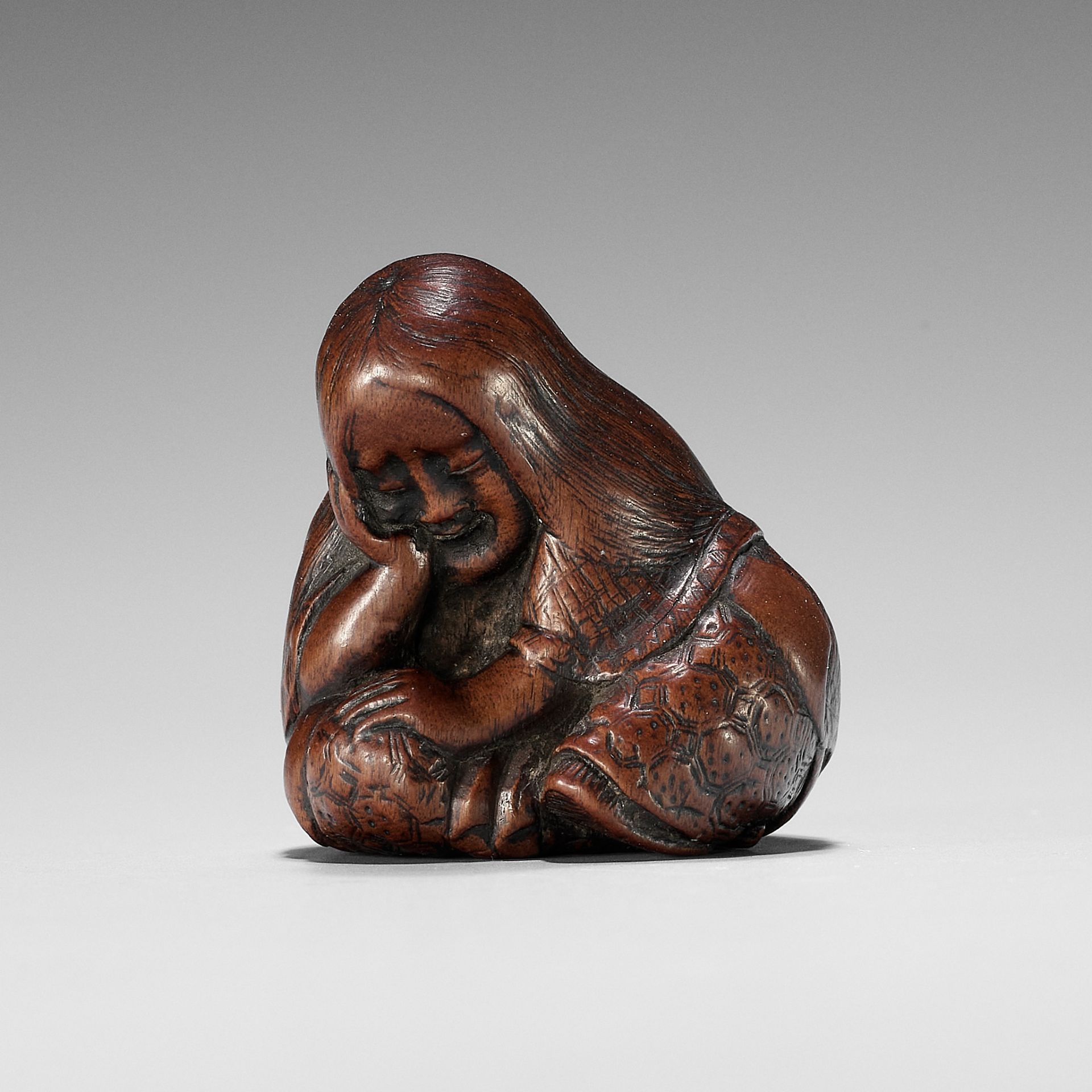 TOSHIKAZU: A NAGOYA SCHOOL WOOD NETSUKE OF A SEATED SLEEPING SHOJO