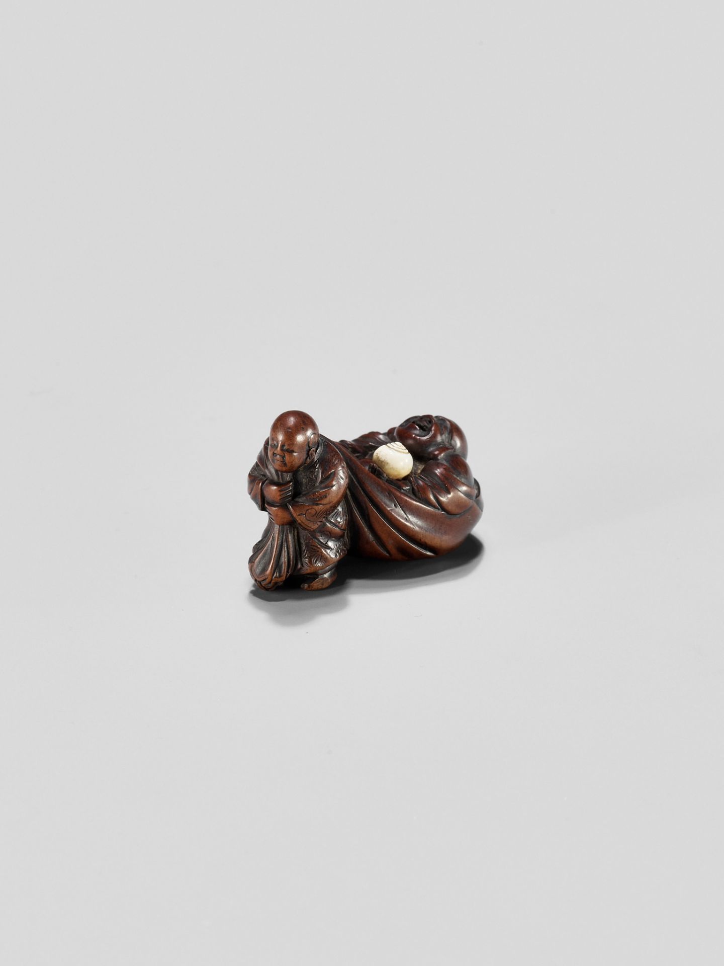 GYOKUMINSAI: A WOOD EDO SCHOOL NETSUKE OF A KARAKO PULLING HOTEI INSIDE HIS TREASURE BAG - Image 8 of 10