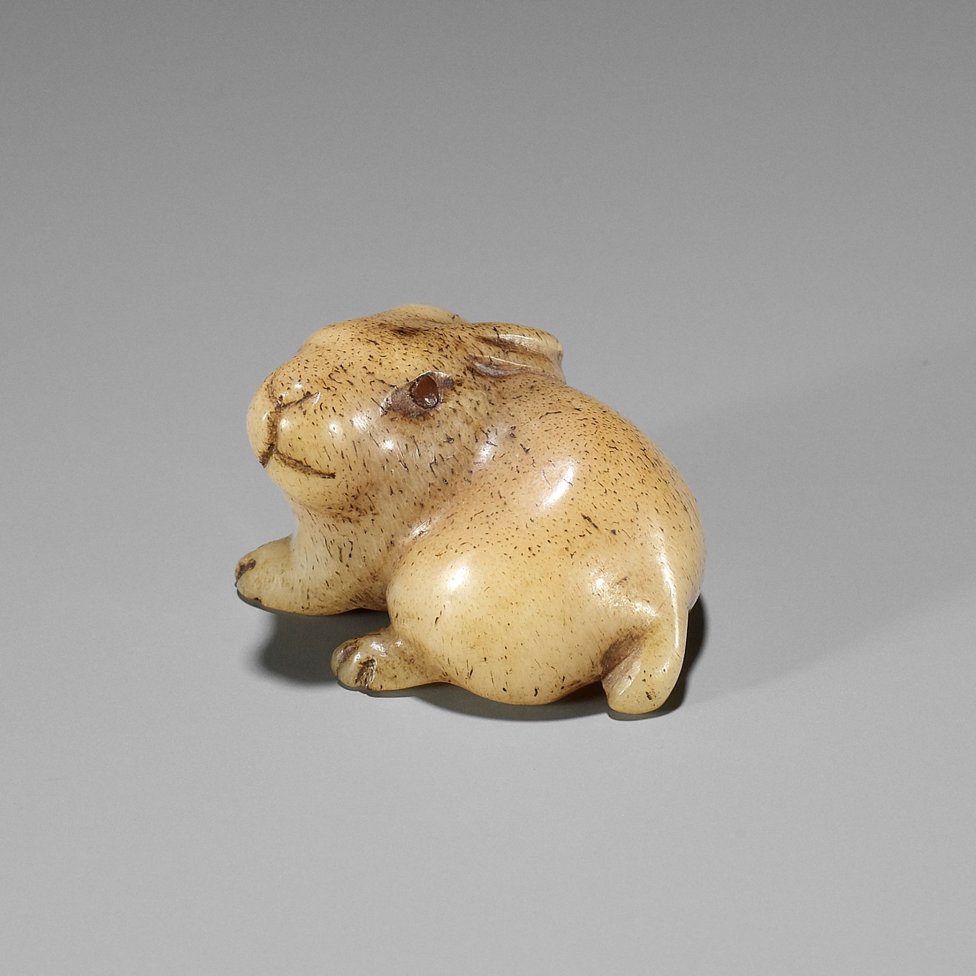 A CHARMING STAG ANTLER NETSUKE OF A HARE