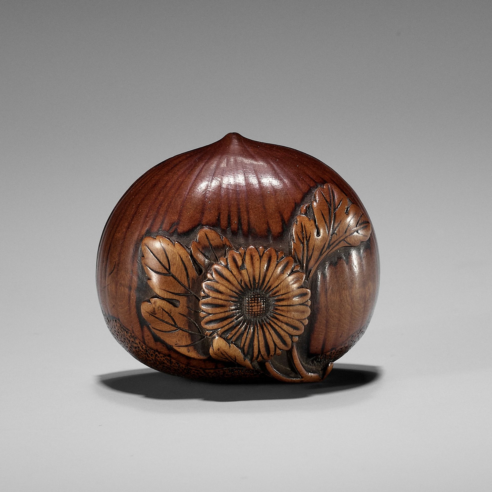 AN EARLY AUTUMNAL WOOD NETSUKE OF A CHESTNUT WITH CHRYSANTHEMUM