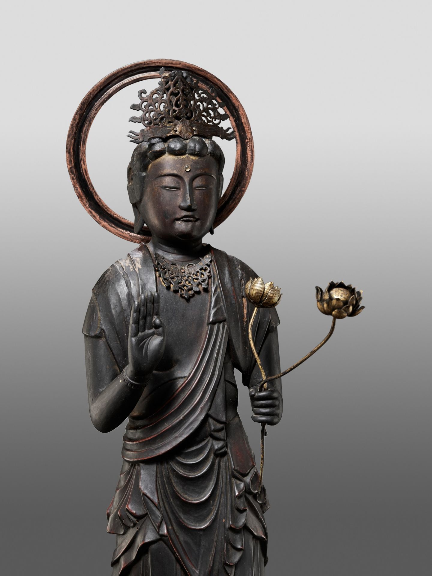 A GILT AND LACQUERED WOOD FIGURE OF KANNON BOSATSU HOLDING LOTUS BLOSSOMS