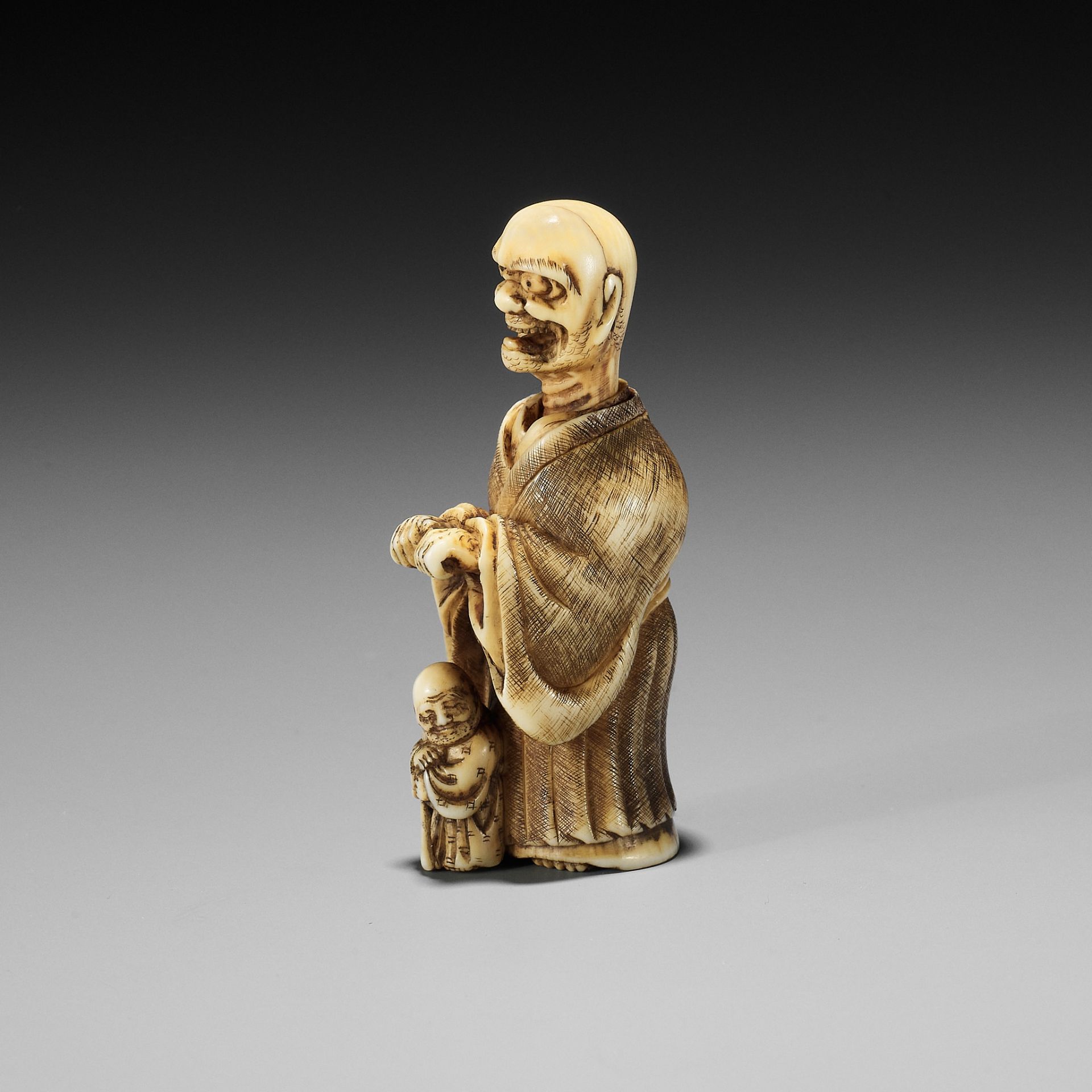 SHURAKU: A RARE IVORY NETSUKE OF A ROKUROKUBI SCARING A BLIND MAN