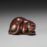 AN EARLY WOOD NETSUKE OF A CAT DEVOURING A FISH