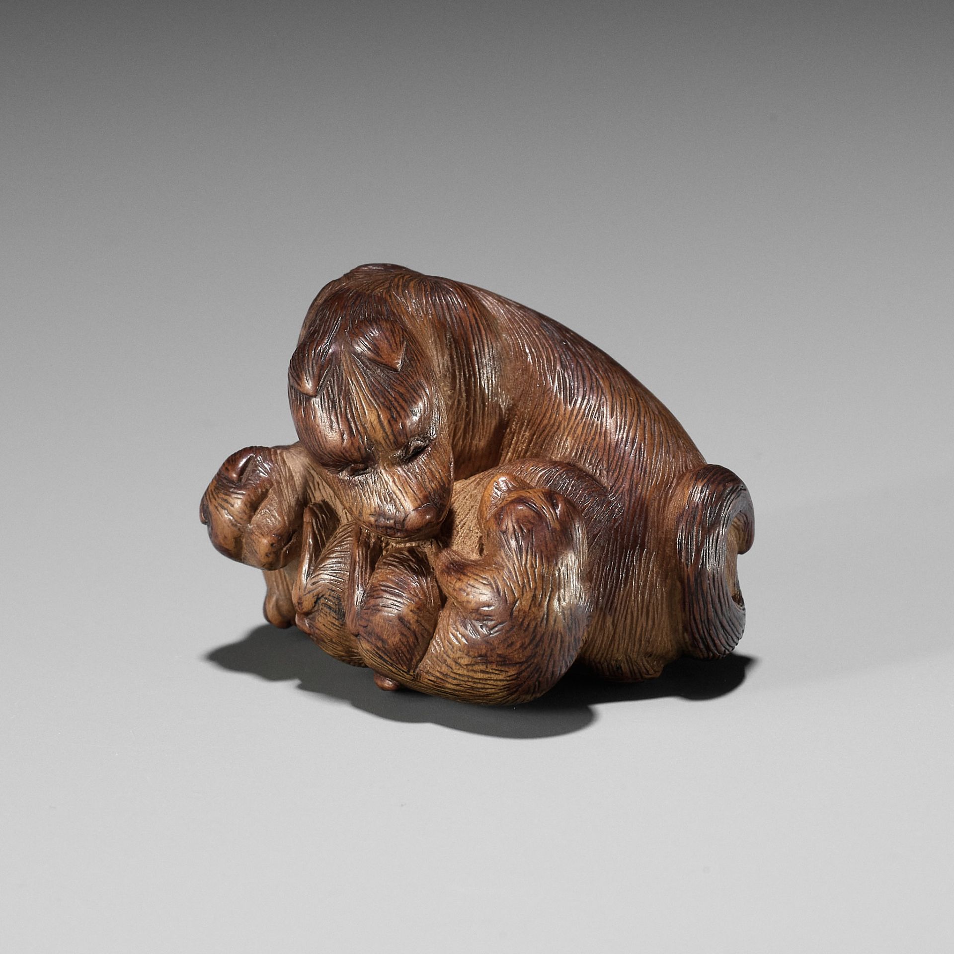 SHIGEHIRO: A CHARMING WOOD NETSUKE OF A DOG AND TWO PUPS