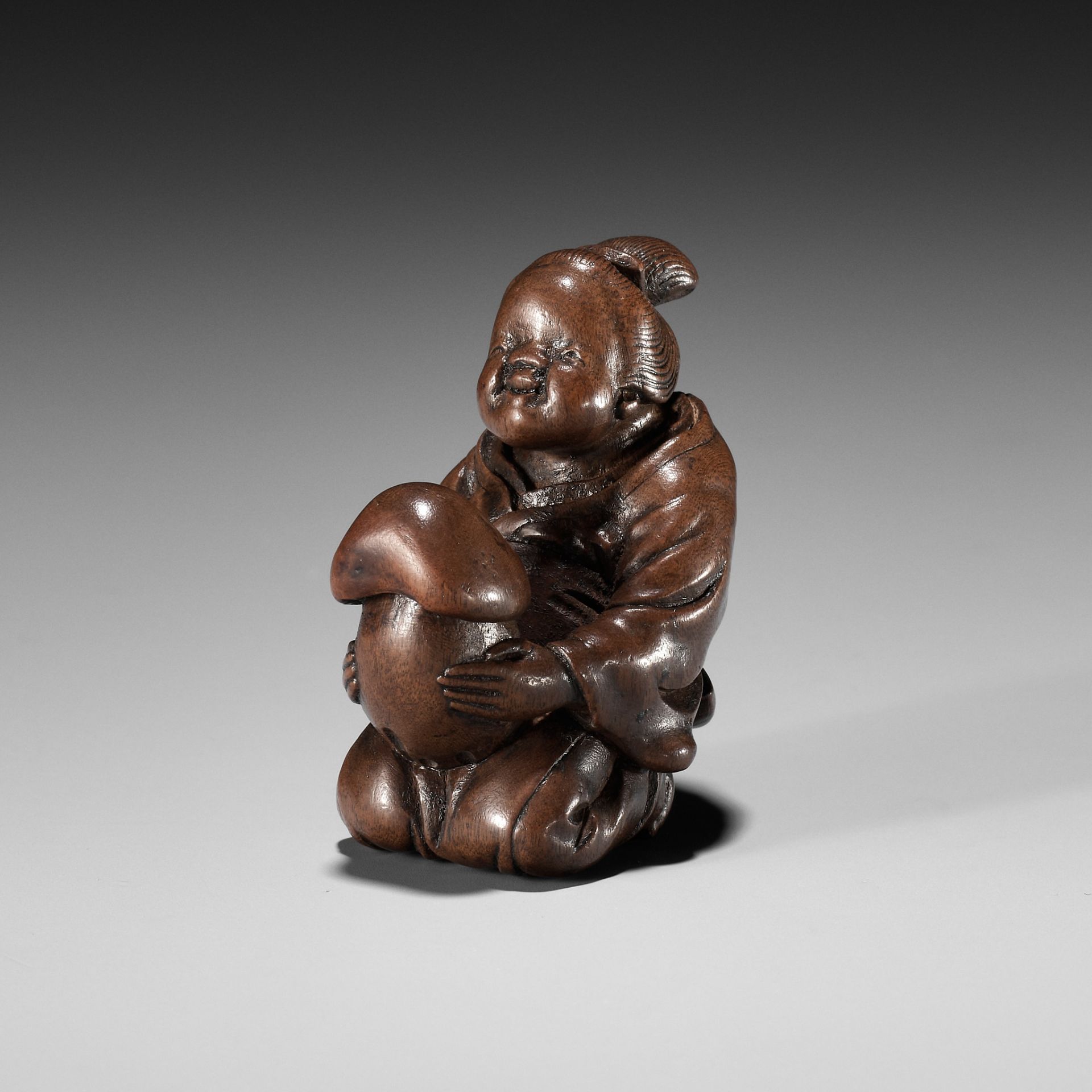 A FINE NAGOYA SCHOOL SHUNGA WOOD NETSUKE OF OKAME CRADLING A HUGE MUSHROOM