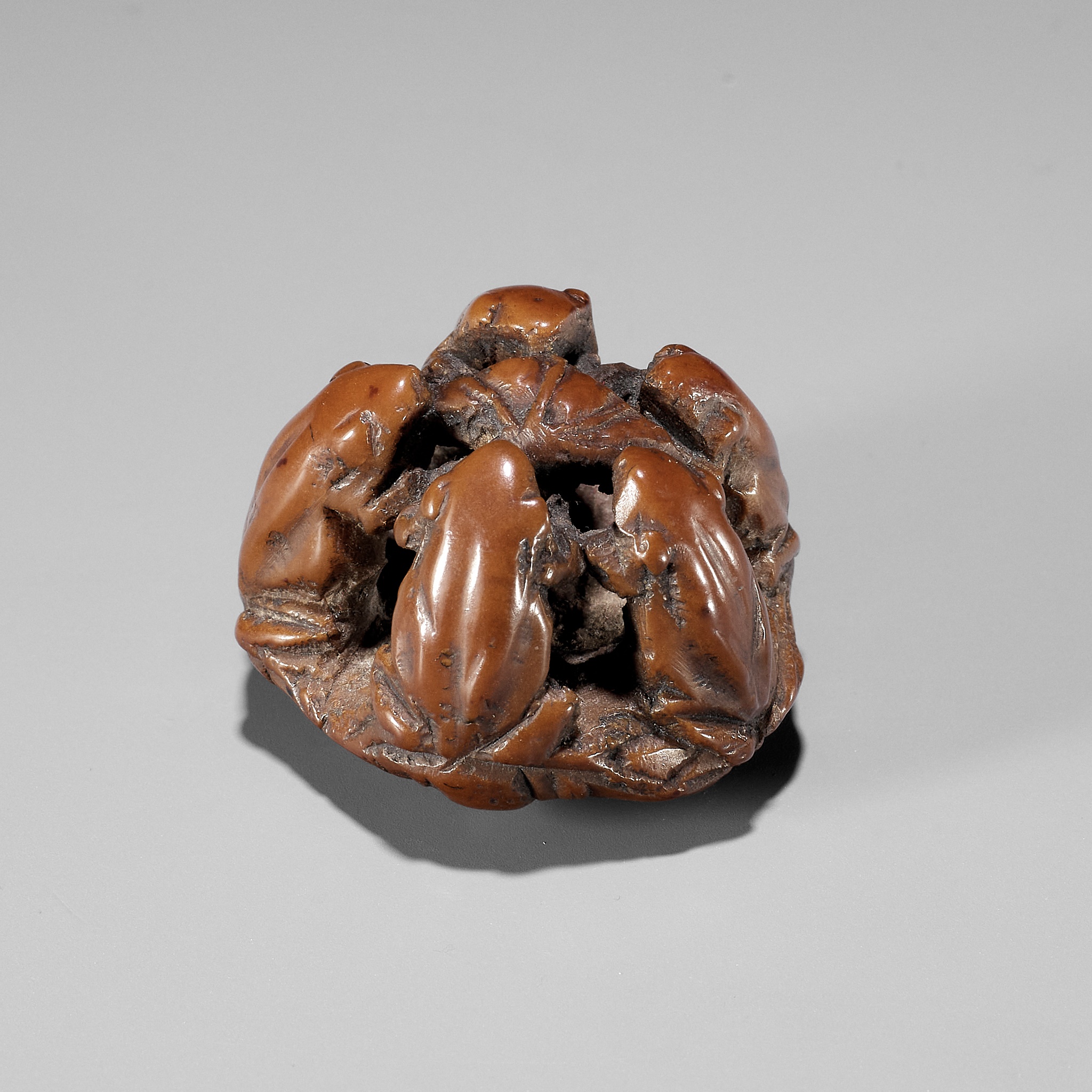 A RARE NUT NETSUKE OF FIVE FROGS ON A LOTUS LEAF, ATTRIBUTED TO SEIMIN