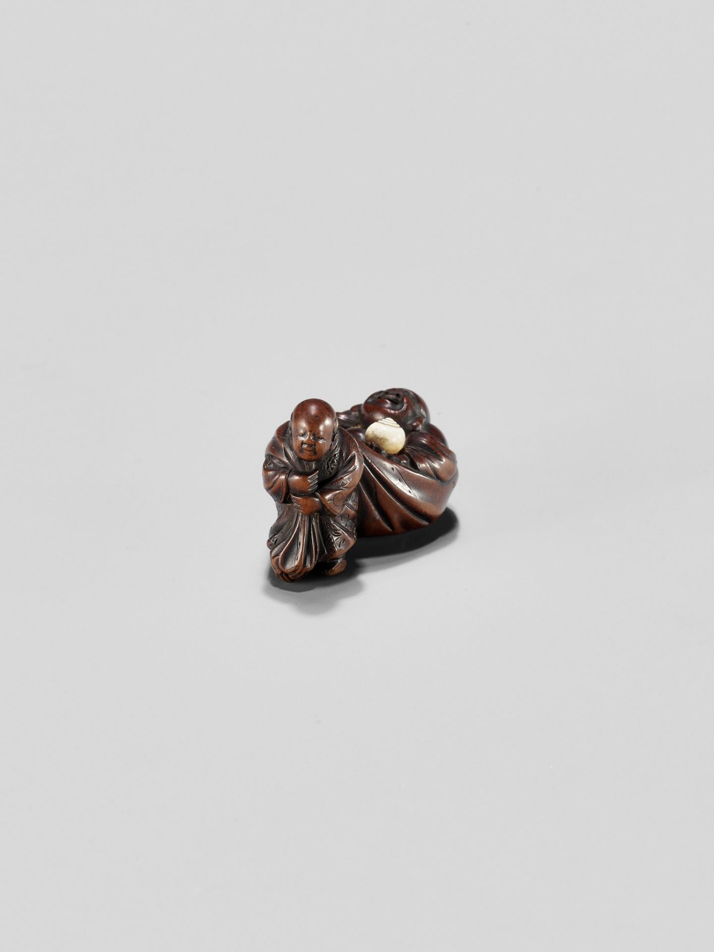 GYOKUMINSAI: A WOOD EDO SCHOOL NETSUKE OF A KARAKO PULLING HOTEI INSIDE HIS TREASURE BAG - Image 2 of 10