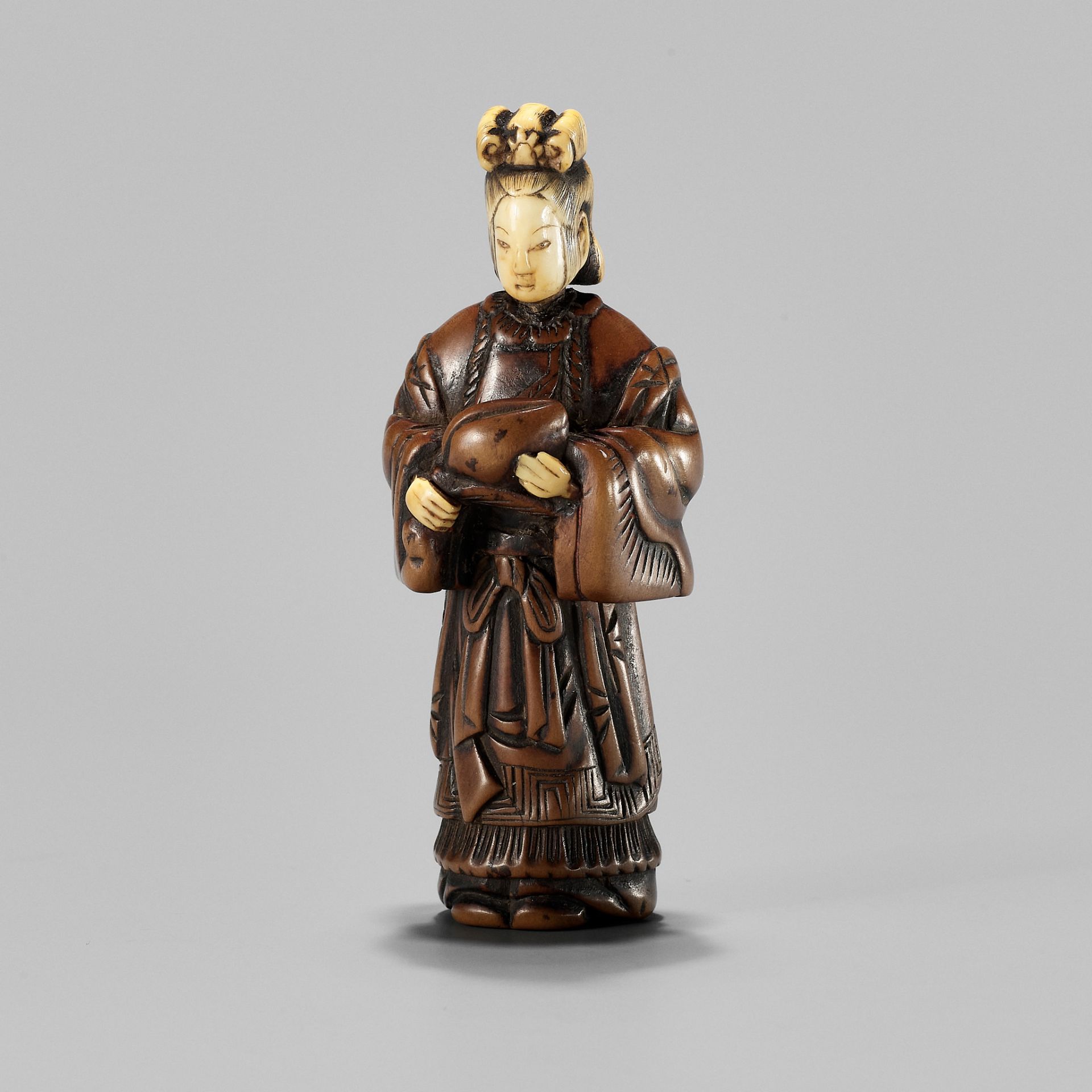 AN INLAID WOOD NETSUKE OF SEIOBO WITH THE PEACH OF IMMORTALITY