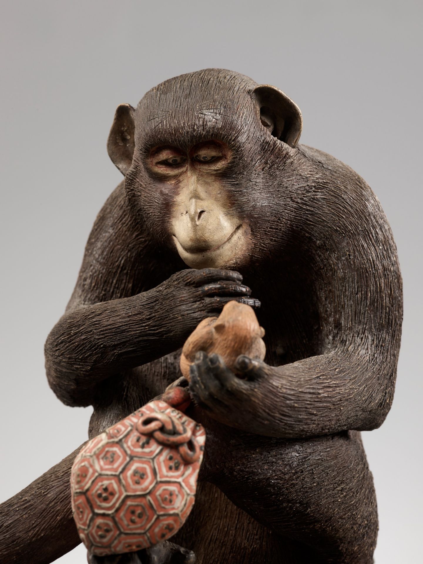 A RARE AND LARGE PAINTED POTTERY OKIMONO OF A MONKEY EXAMINING A MONKEY NETSUKE