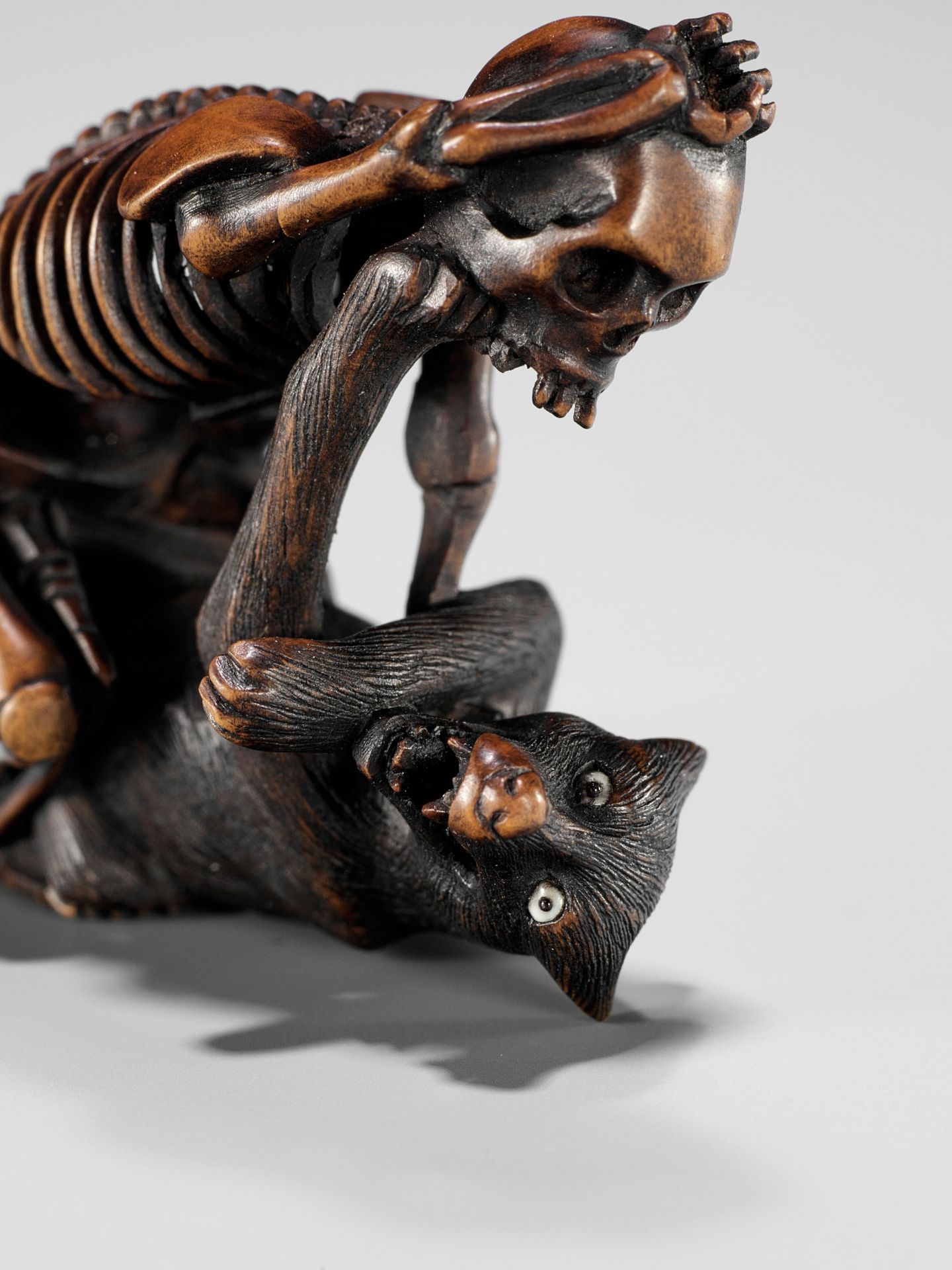 A FINE WOOD NETSUKE OF A WOLF AND SKELETON, ATTRIBUTED TO SHOKO