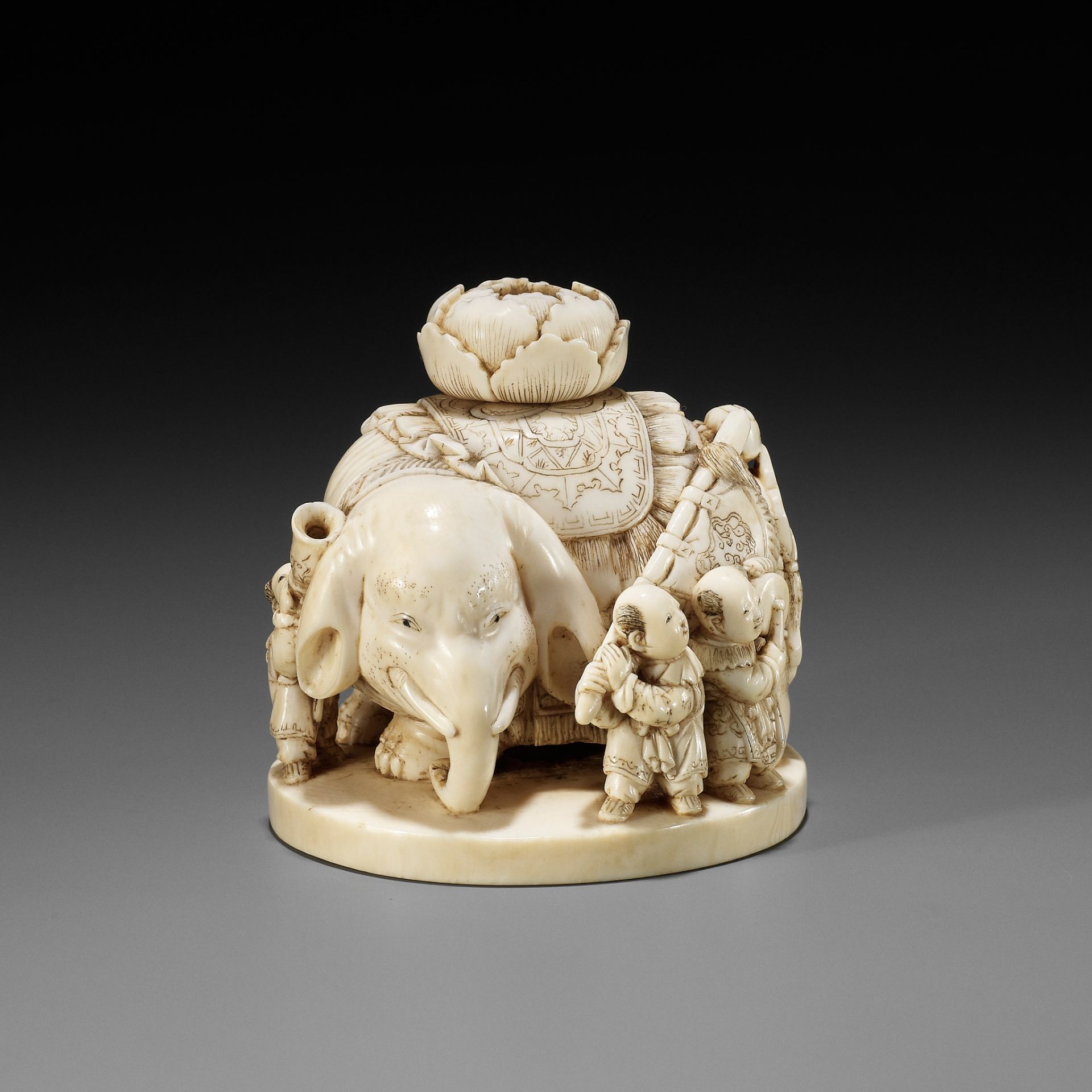 CHIKUYOSAI TOMOCHIKA: A LARGE IVORY OKIMONO NETSUKE OF AN ELEPHANT WITH A GROUP OF KARAKO