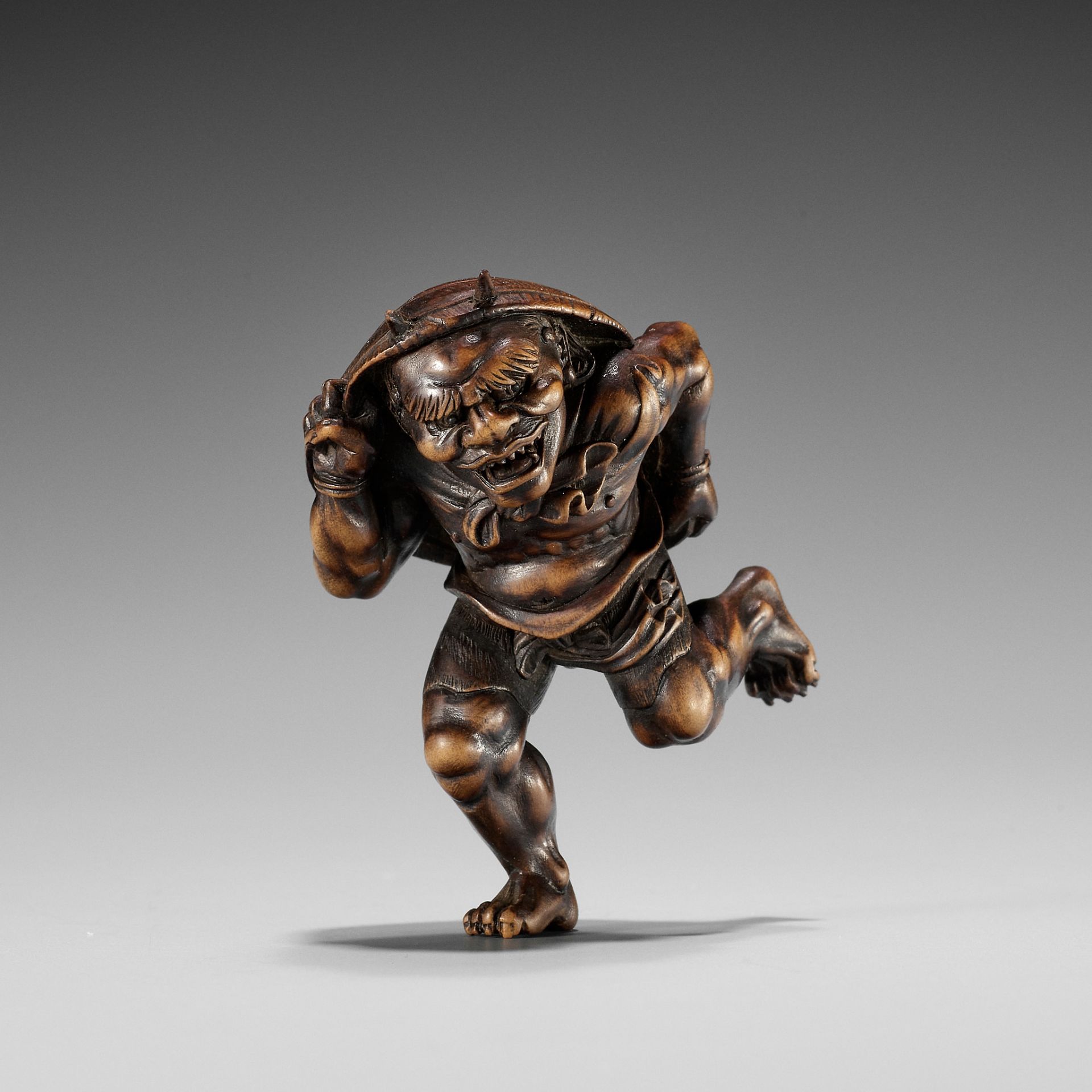 A WOOD NETSUKE OF AN ONI AT SETSUBUN, ATTRIBUTED TO ROKKO