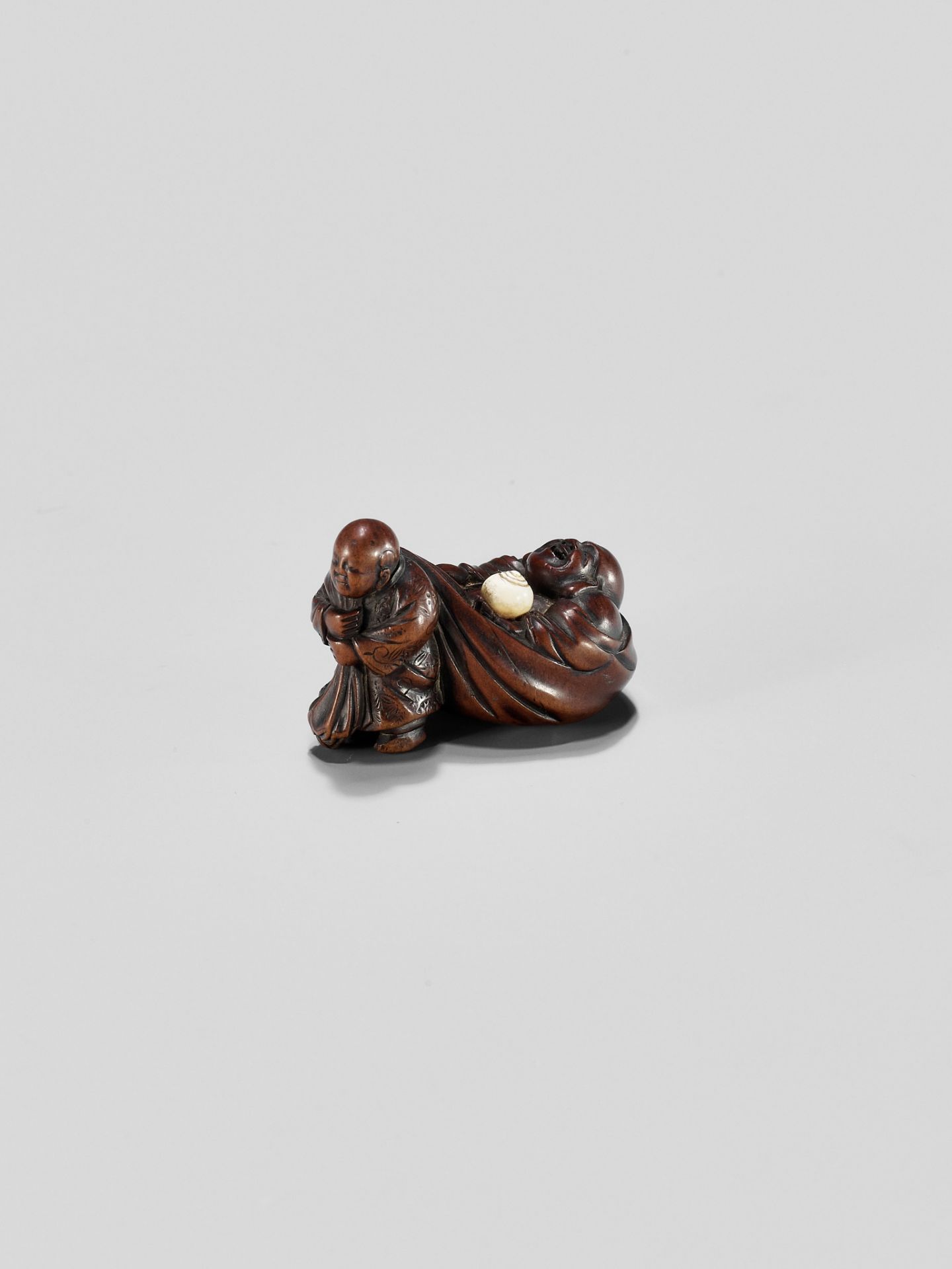 GYOKUMINSAI: A WOOD EDO SCHOOL NETSUKE OF A KARAKO PULLING HOTEI INSIDE HIS TREASURE BAG - Image 3 of 10