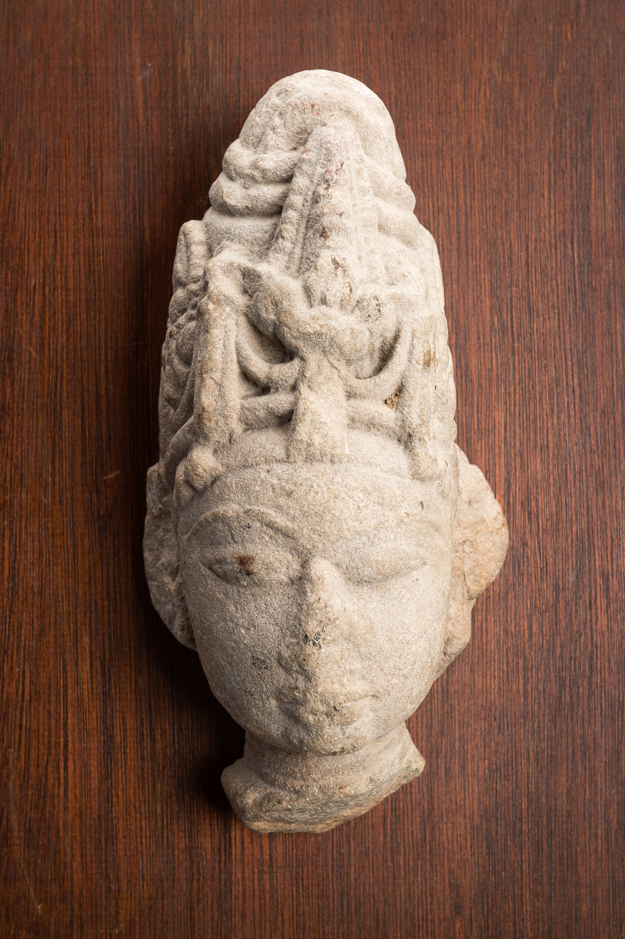 A SANDSTONE HEAD OF VISHNU WITH A MITER CROWN