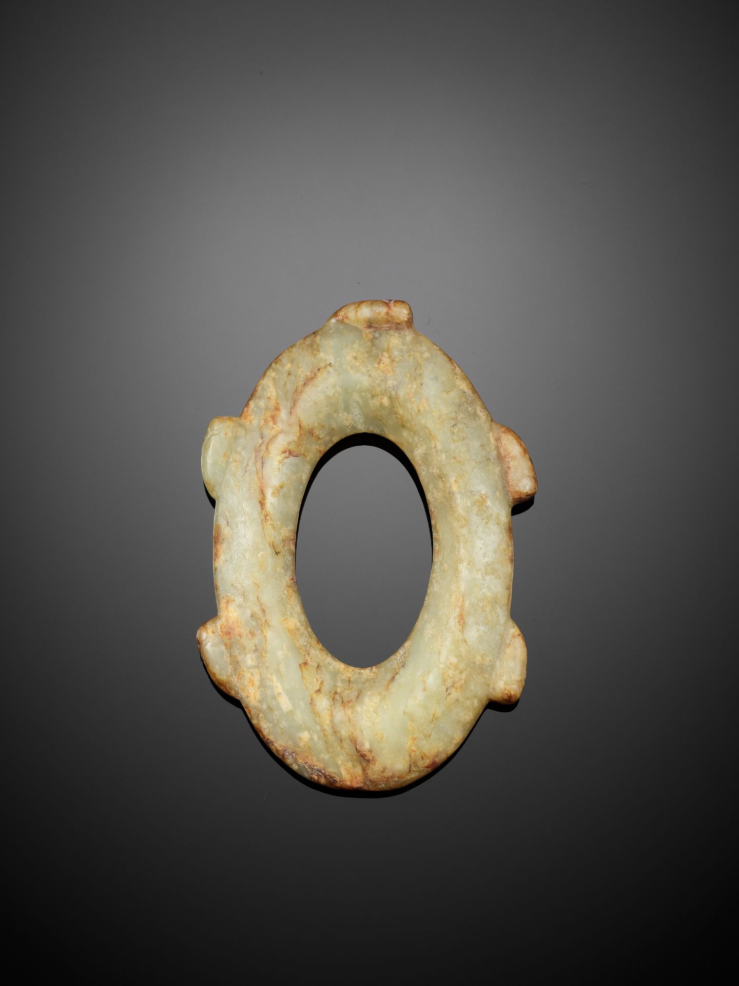 AN ARCHAISTIC CELADON AND RUSSET OVAL JADE DISC