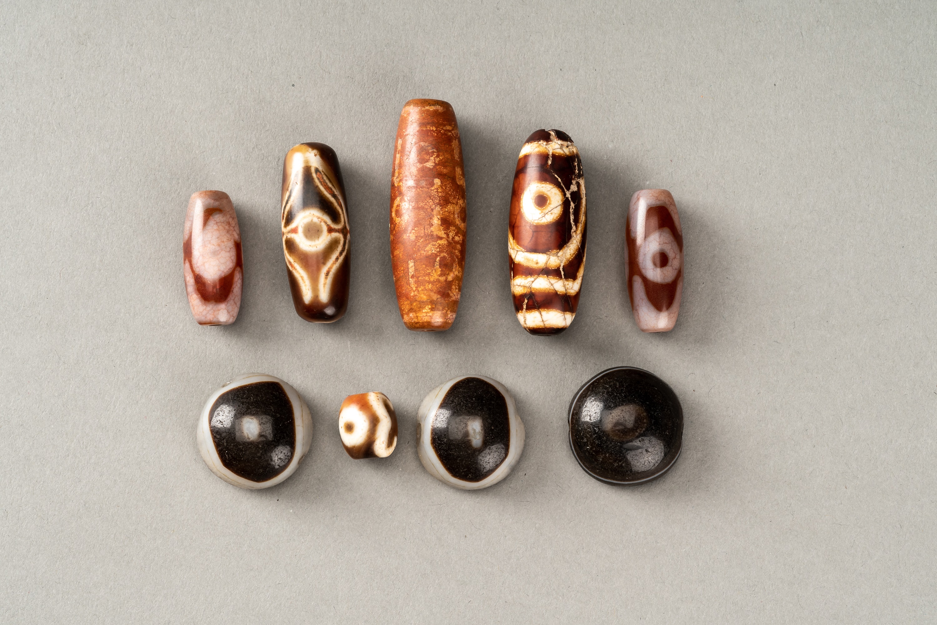 A GROUP OF NINE TIBETAN AGATE DZI AND BUDDHA EYE BEADS