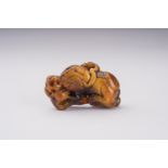 A RARE AMBER CARVING OF A BUDDHIST LION WITH BALL