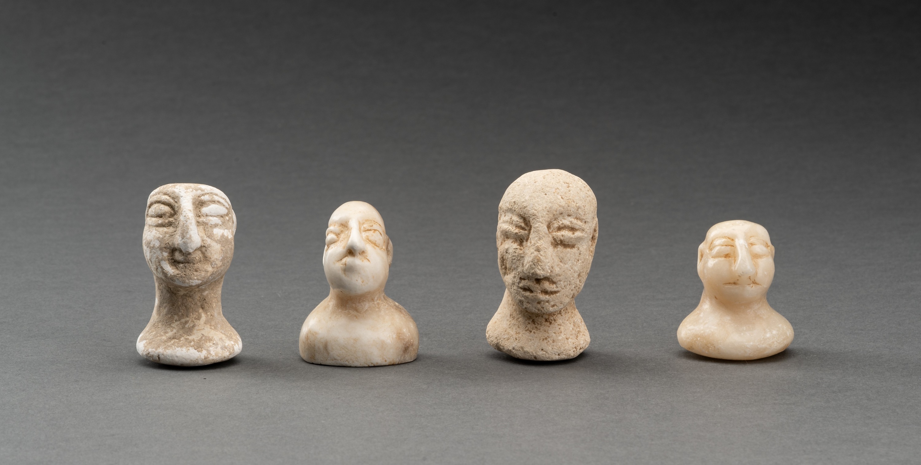 A LOT WITH FOUR BACTRIAN WHITE MARBLE AND STONE IDOL HEADS