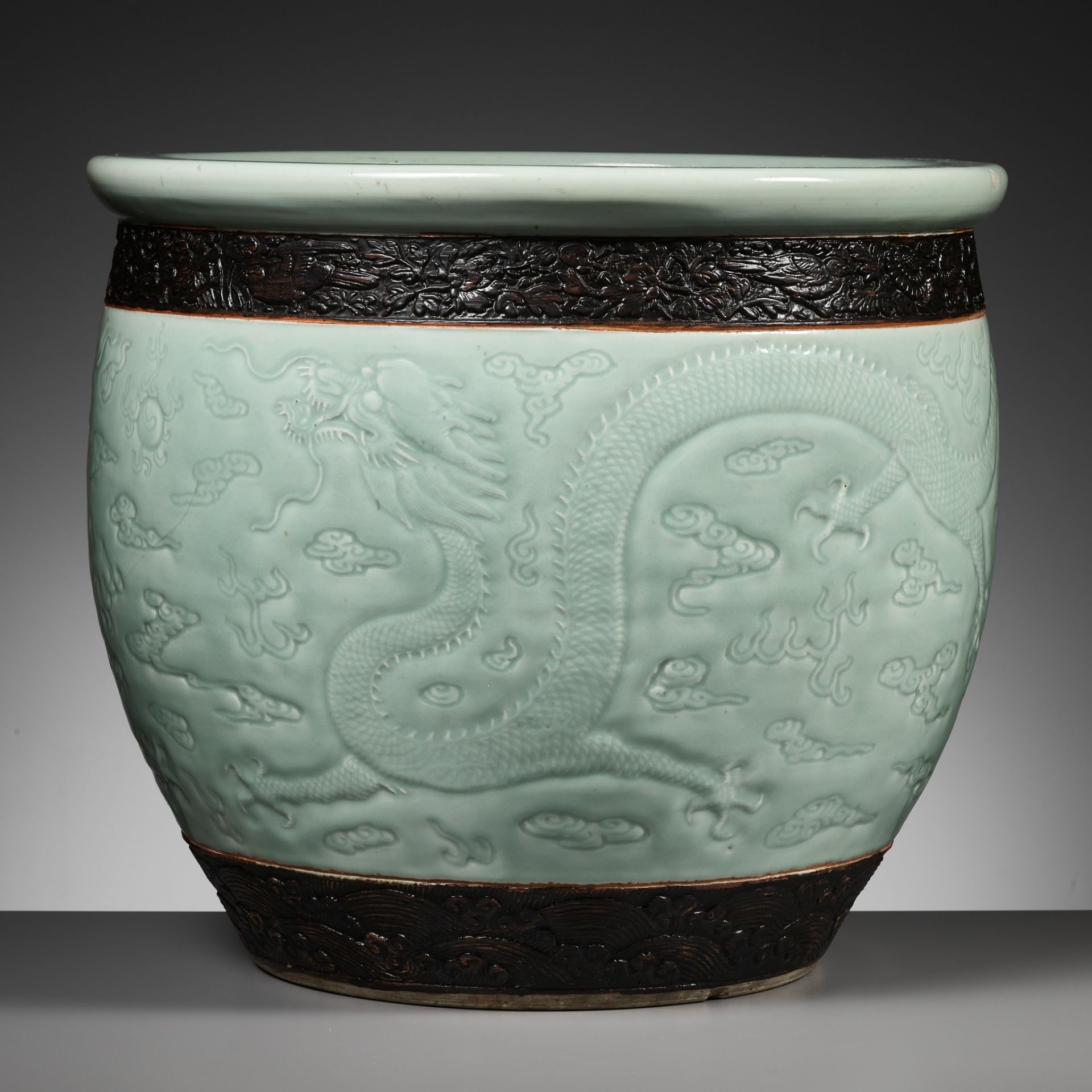 A LARGE MOLDED AND CARVED CELADON-GLAZED 'DRAGON' FISHBOWL, QING DYNASTY