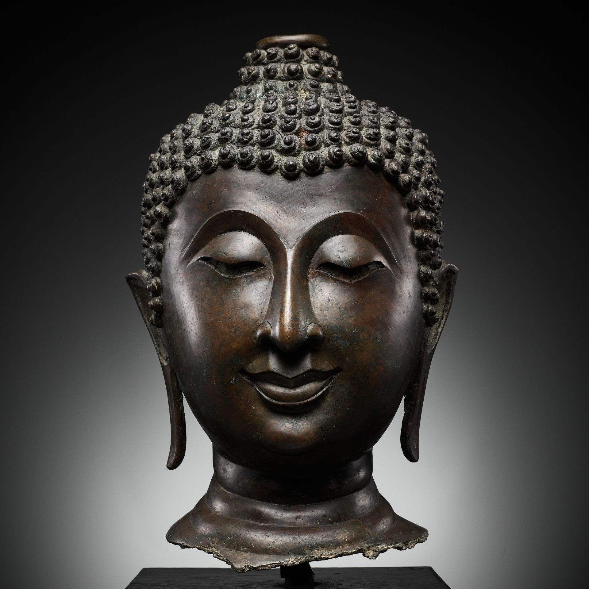 A MONUMENTAL BRONZE HEAD OF BUDDHA, LAN NA, NORTHERN THAILAND, 14TH-15th CENTURY