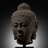 AN IMPORTANT OVER-LIFESIZE ANDESITE HEAD OF BUDDHA, CENTRAL JAVANESE PERIOD, INDONESIA, 9TH CENTURY