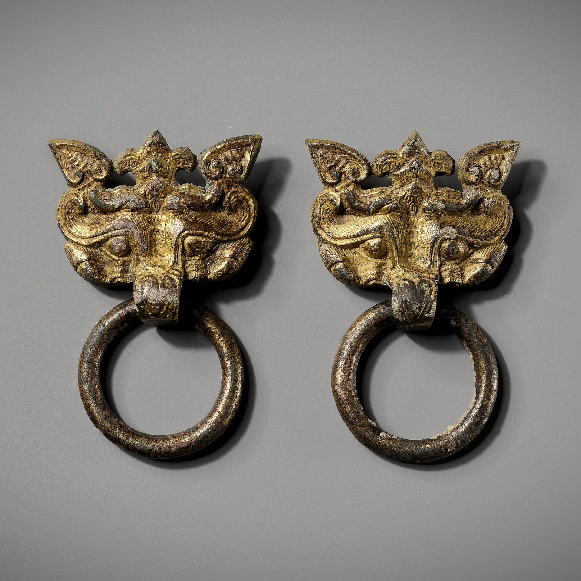 A PAIR OF GILT-BRONZE TAOTIE MASKS WITH RING HANDLES, WARRING STATES TO HAN DYNASTY