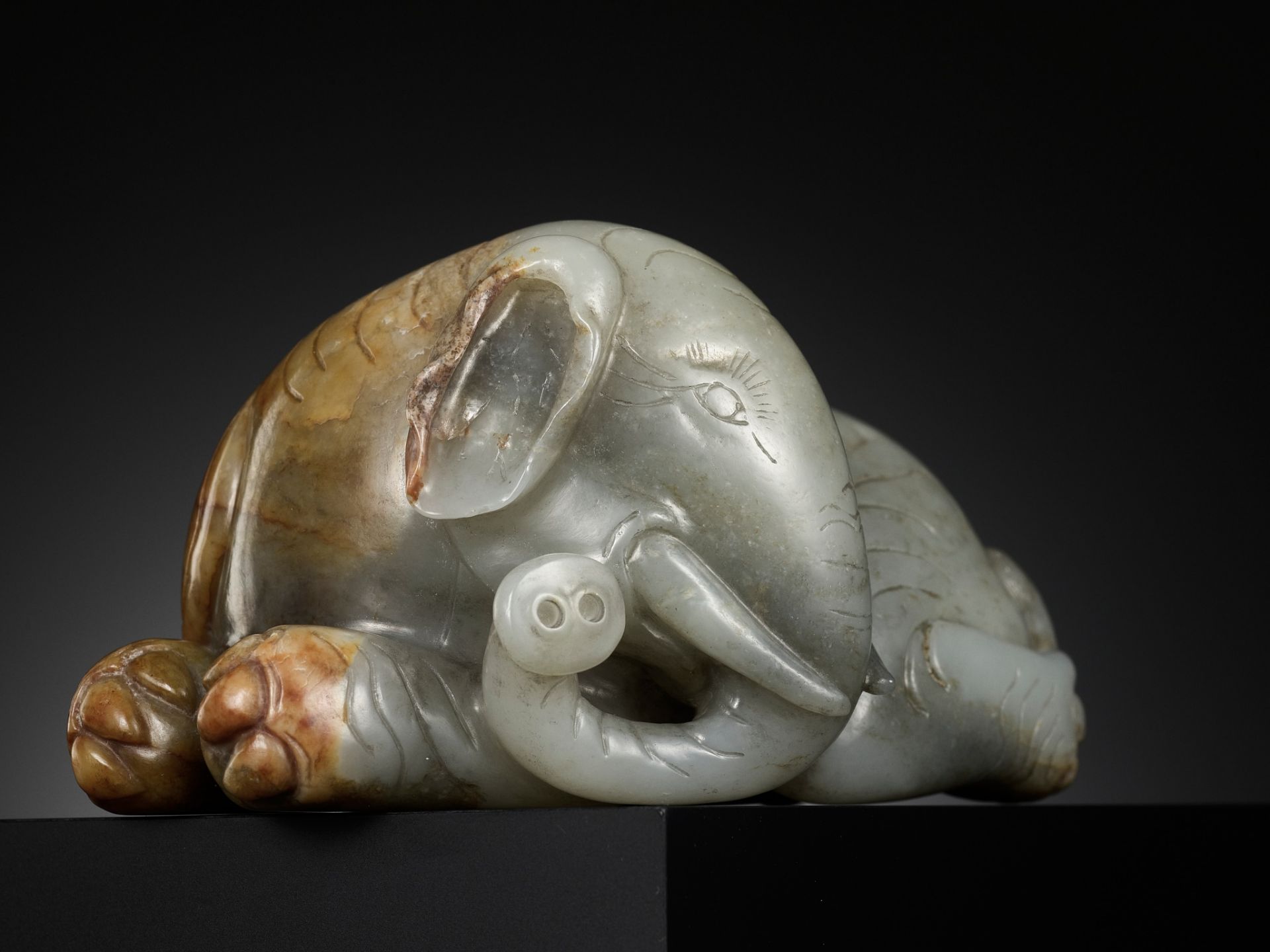 A GRAY AND RUSSET JADE FIGURE OF A RECUMBENT ELEPHANT, LATE MING TO MID-QING DYNASTY