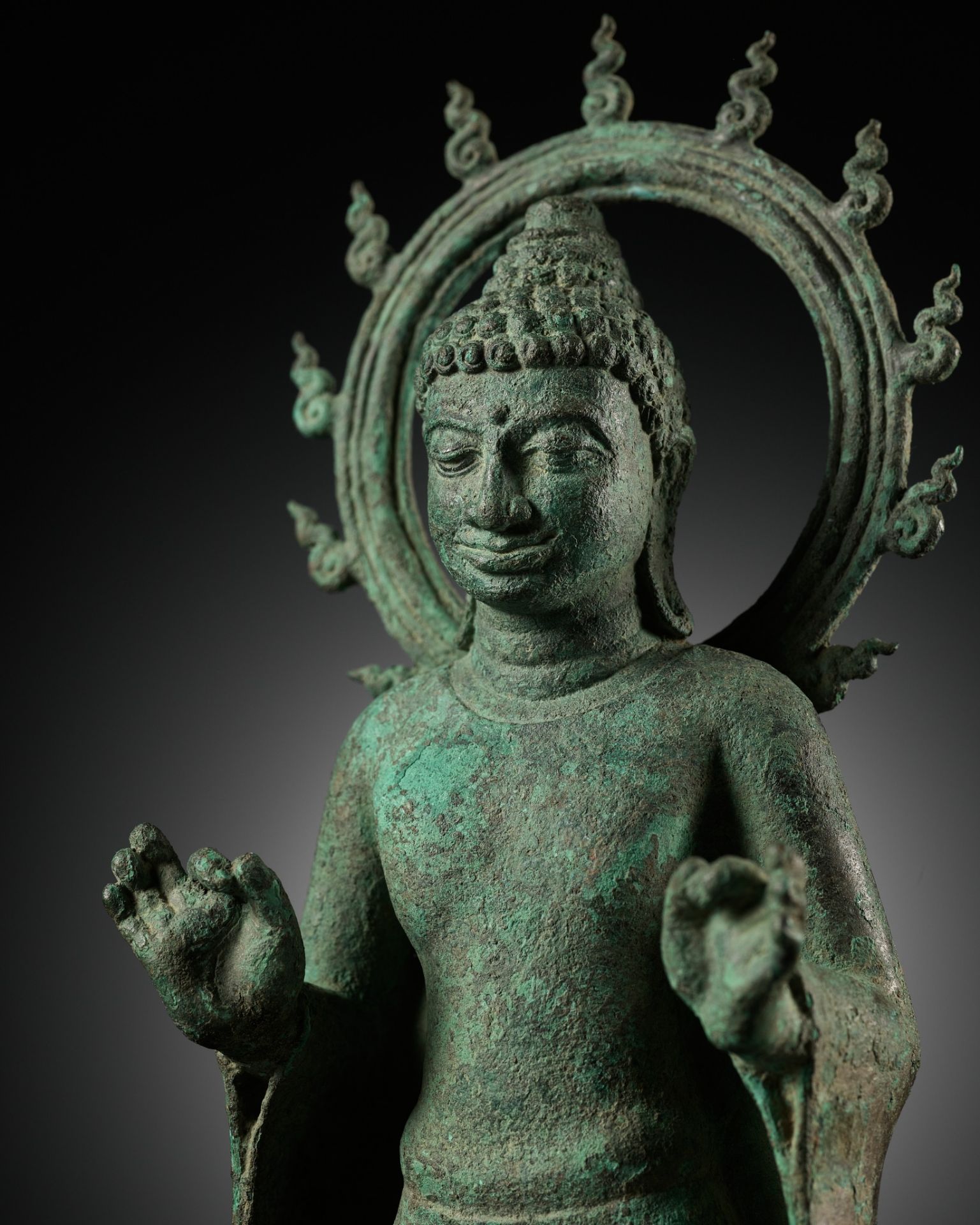 A BRONZE STATUE OF BUDDHA WITHIN A FLAMING AUREOLE, INDONESIA, CENTRAL JAVA, 8TH-9TH CENTURY