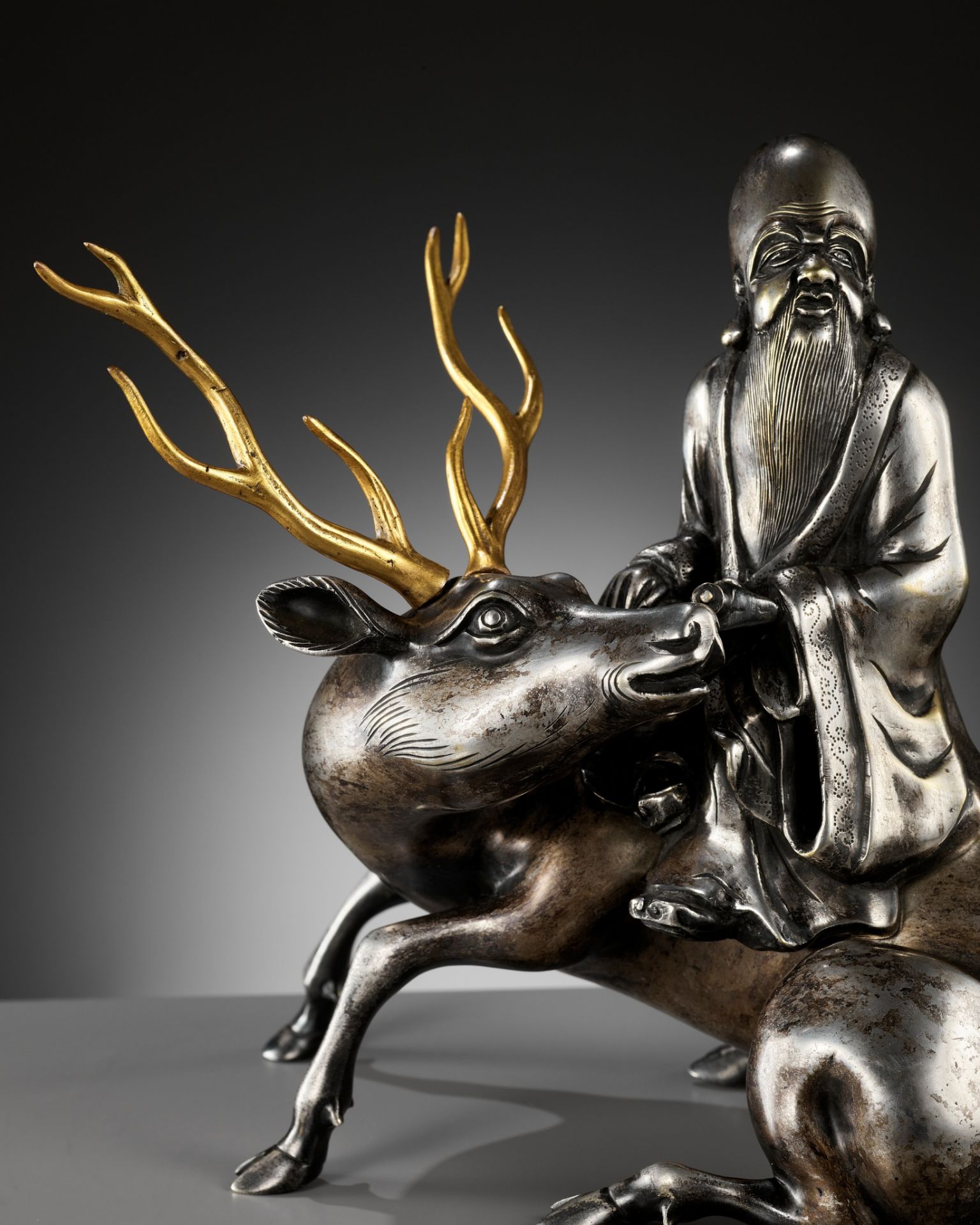 A SILVERED AND GILT BRONZE 'SHOULAO AND DEER' INCENSE BURNER, QING DYNASTY