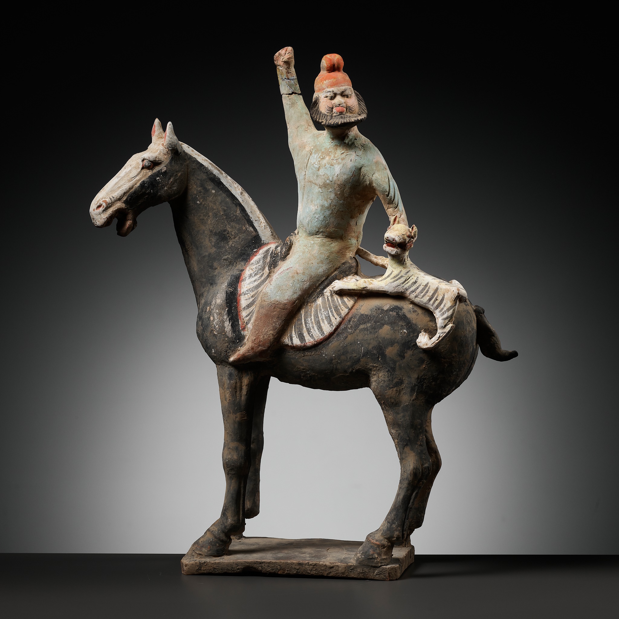 A RARE PAINTED POTTERY HORSE WITH A 'PHRYGIAN' RIDER AND TIGER CUB, TANG DYNASTY
