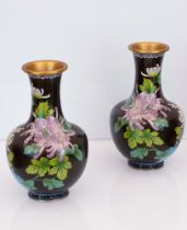Coppia di vasi cloisonnet neri con decori floreali. Basi in legno ebanizzato.